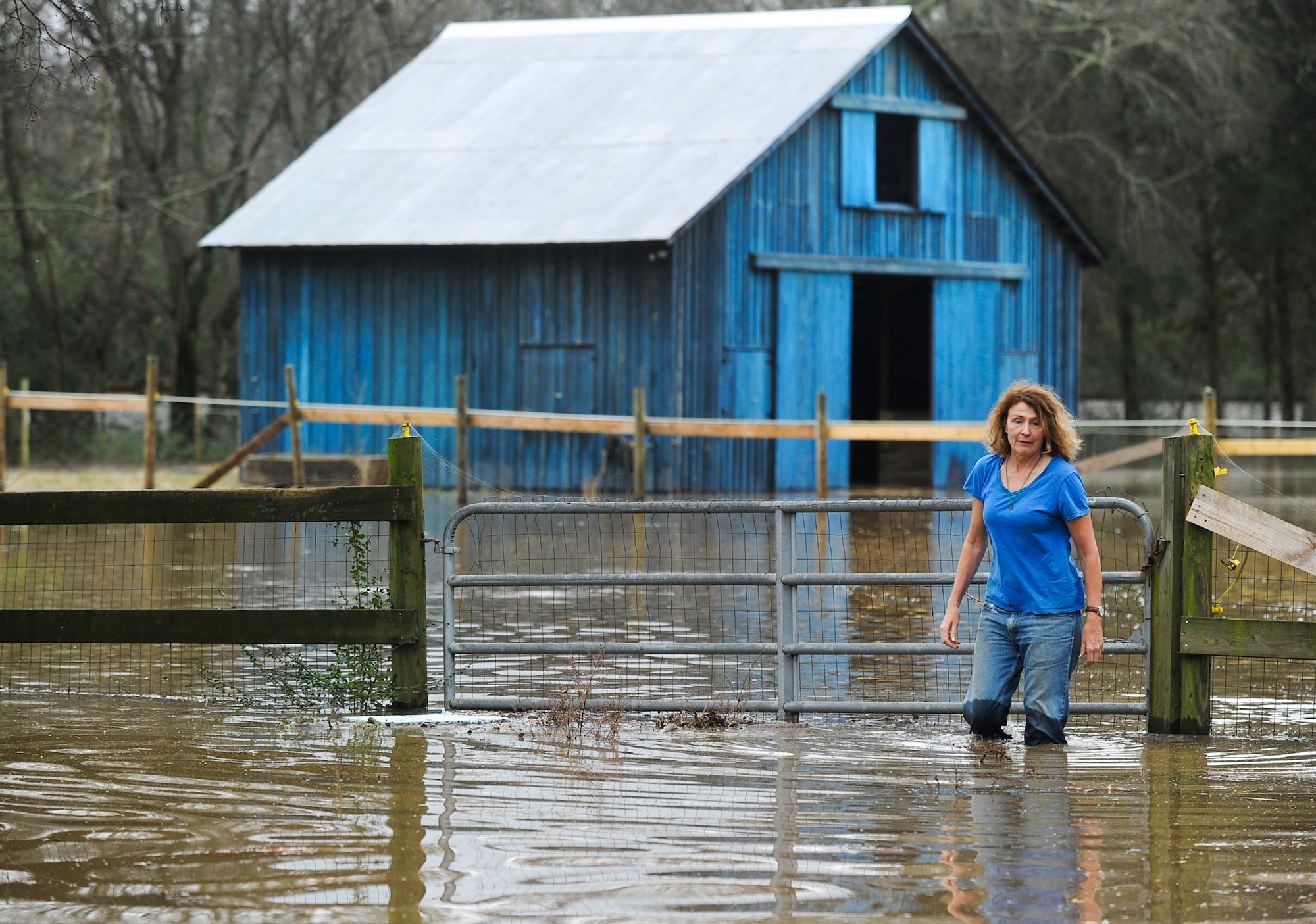 Andrea Simpson wades through water as she goes back to her house in Courtland, Ala., after checking if the barn was safe for her horses to spend the night in Saturday, Dec. 26, 2015. The barn turned out to be flooded, too.