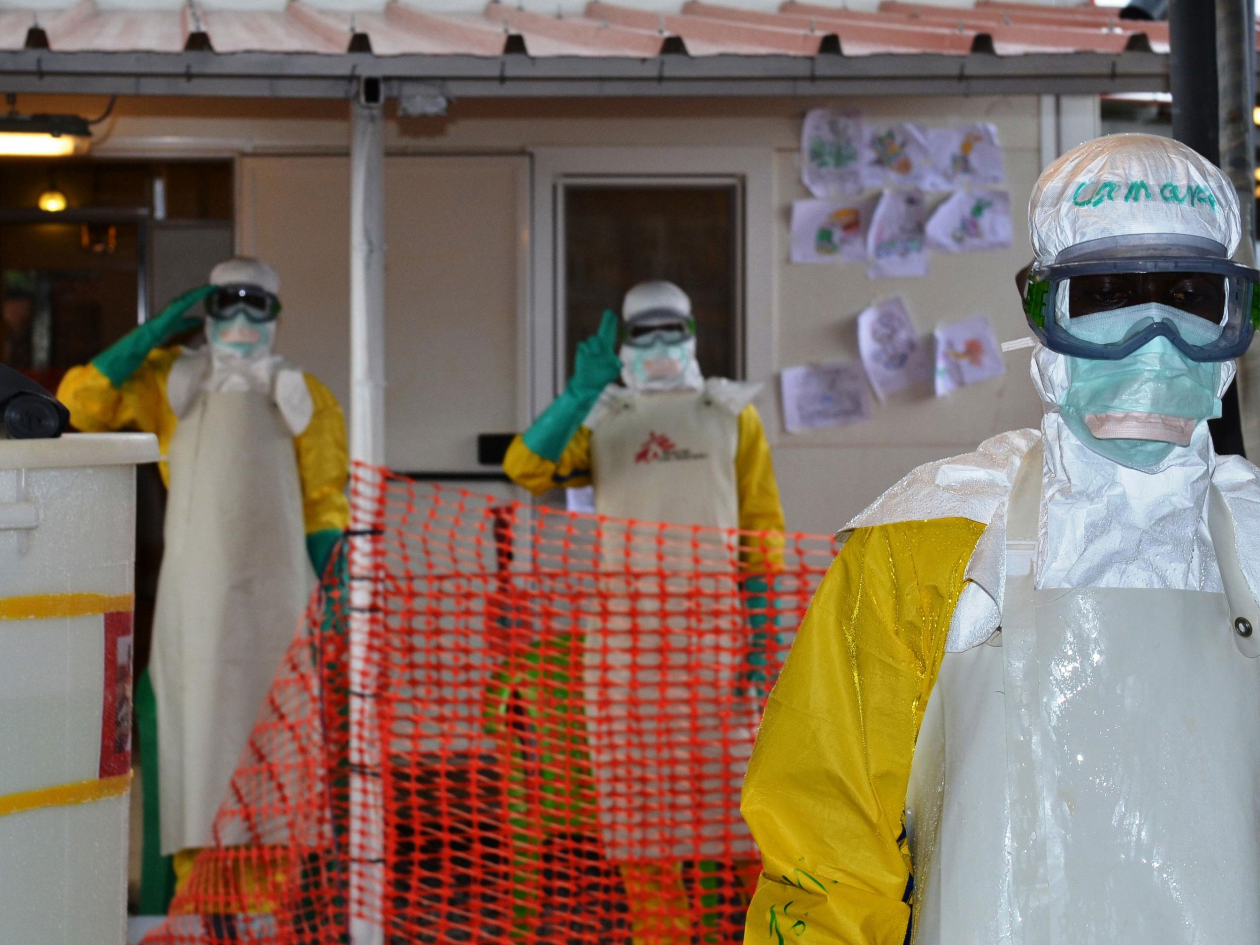 Health workers wearing protective gear gesture at the Nongo ebola treatment centre in Conakry, Guinea