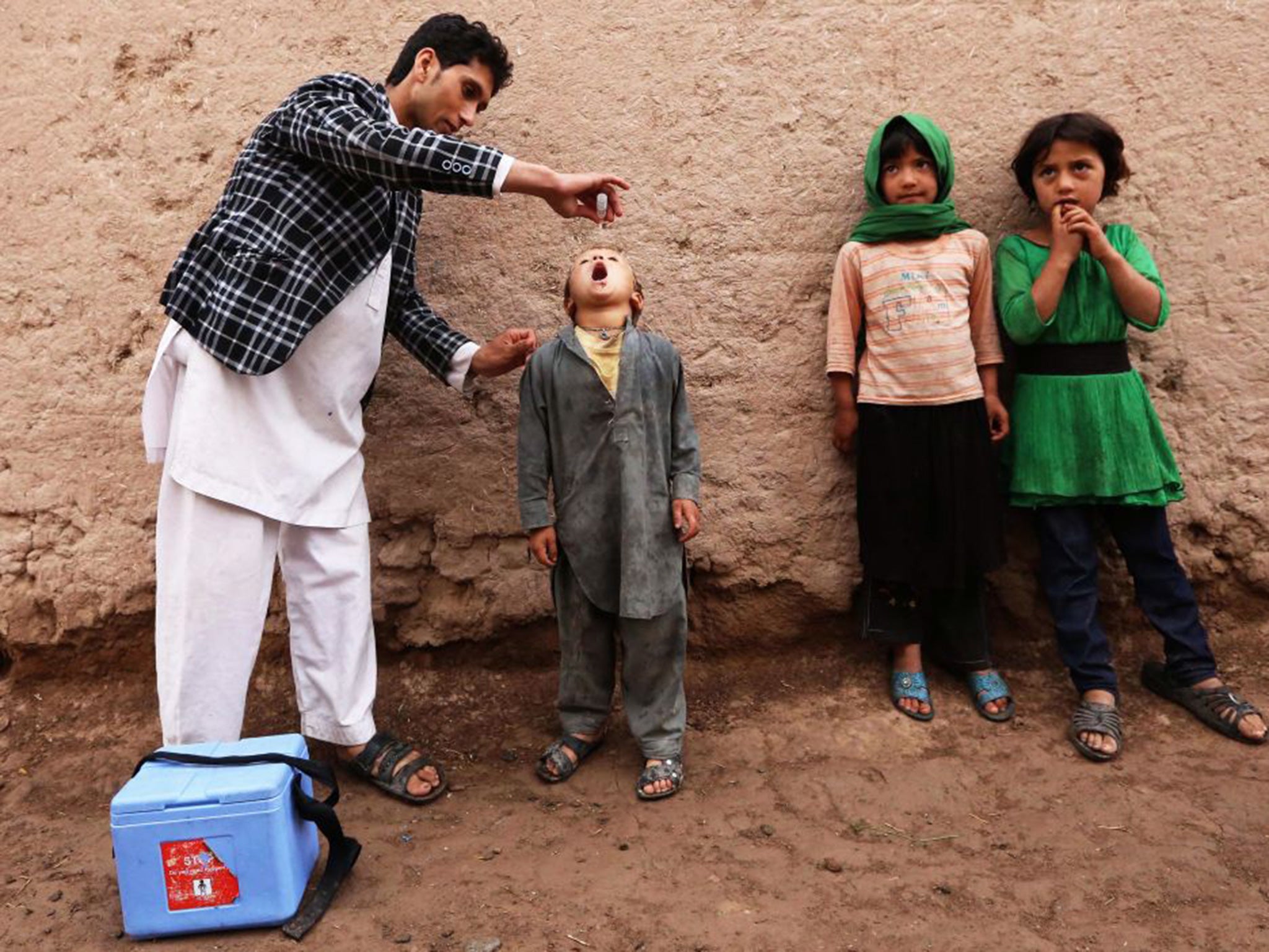 A health worker administers a polio vaccine to a child, in Enjil district of Herat, Afghanistan, 11 May 2015