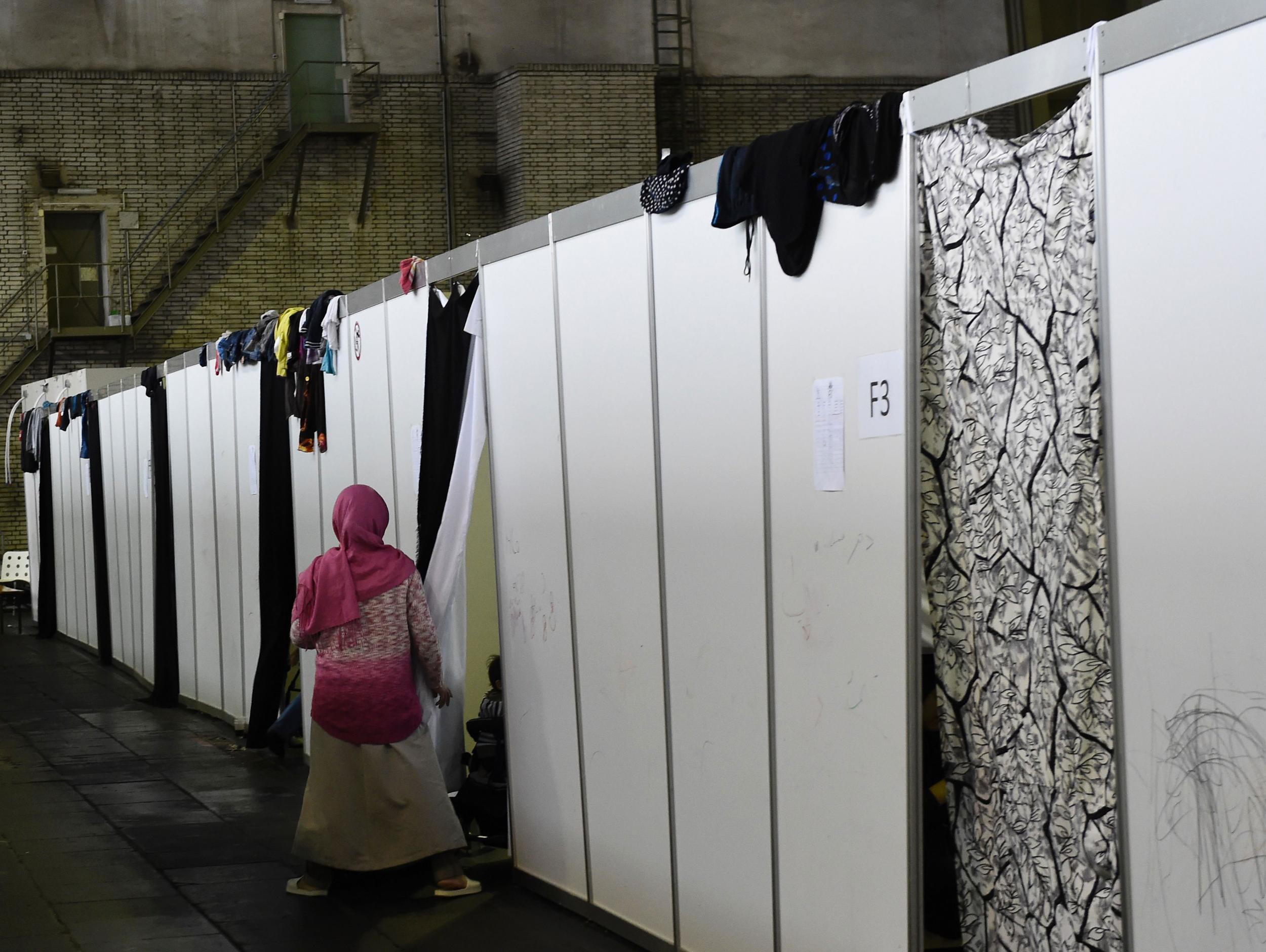 A woman enters a temporary bedroom at a refugee accomodation hosted in a hangar of the former Tempelhof airport in Berlin