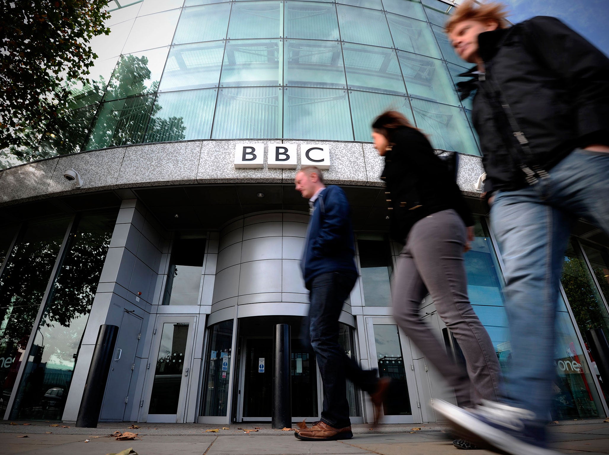 Caption:People walk past one of the entrances to the BBC Television offices in west London, on October 6, 2011