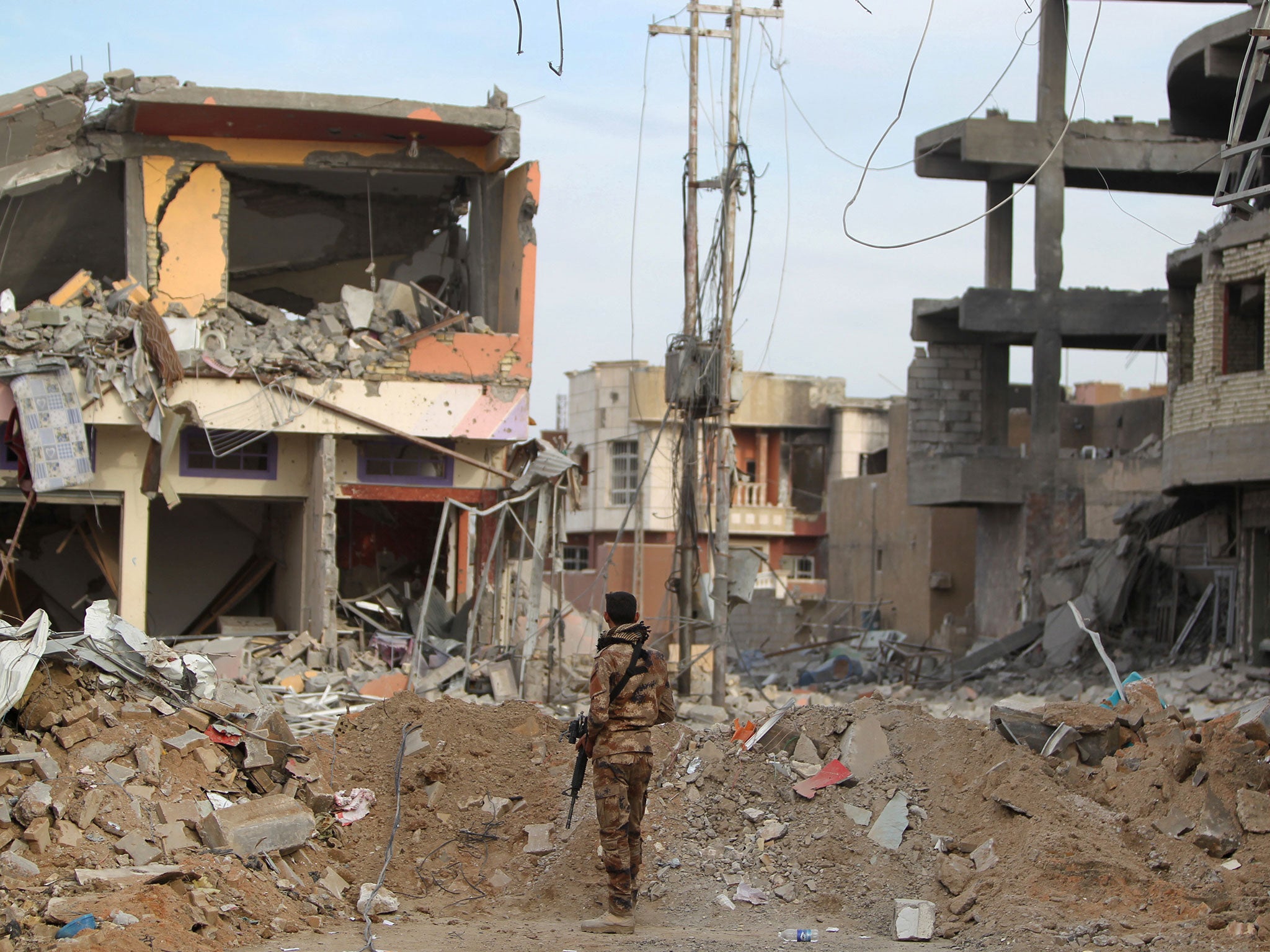 A member of Iraqi pro-government forces stands amid the rubble of destroyed buildings in the Hoz neighbourhood in central Ramadi, the capital of Iraq's Anbar province