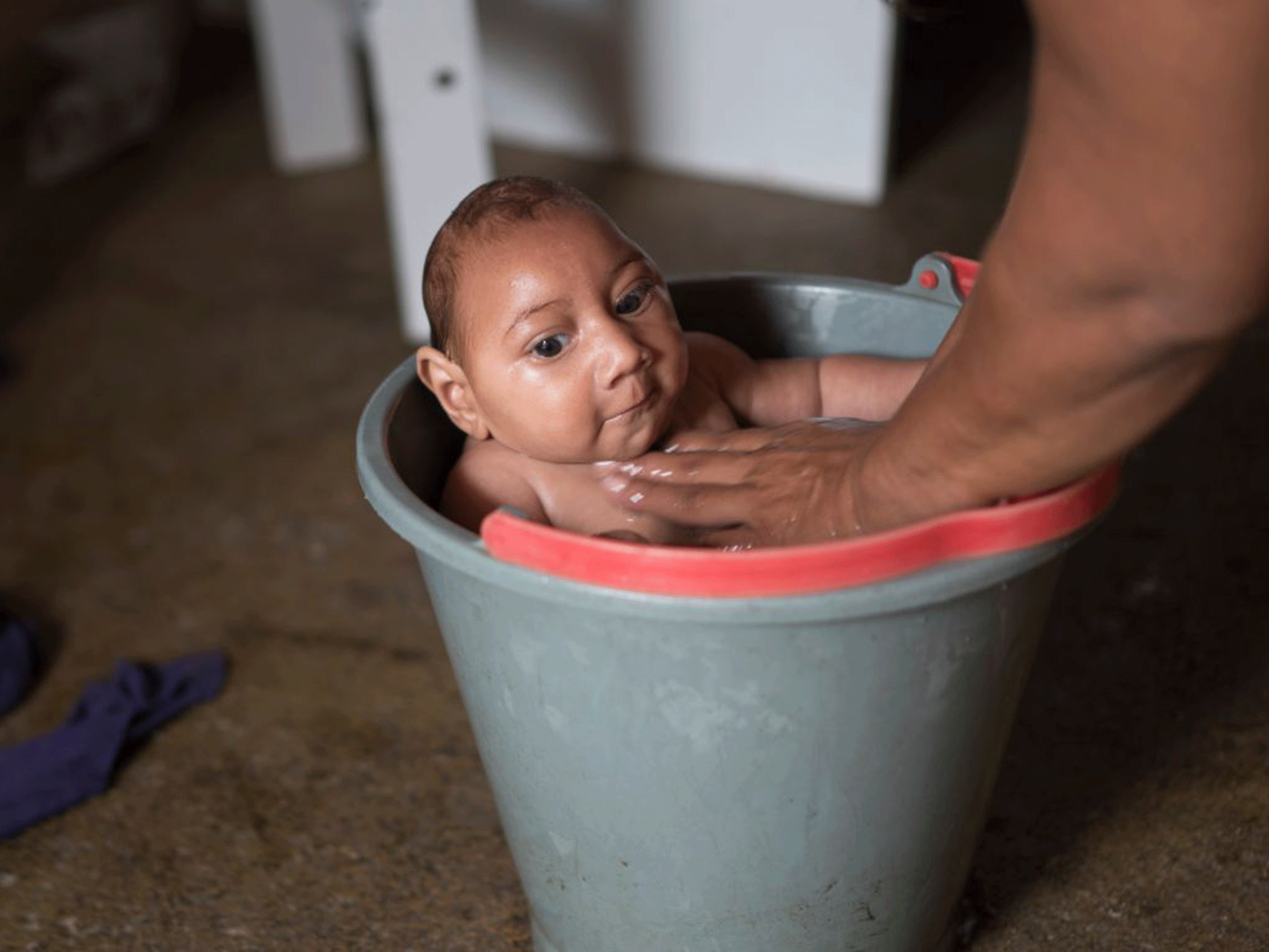 Solange Ferreira bathes her son Jose Wesley in a bucket of water, which she says he enjoys and helps calm him, at their home in Poco Fundo, Brazil Getty