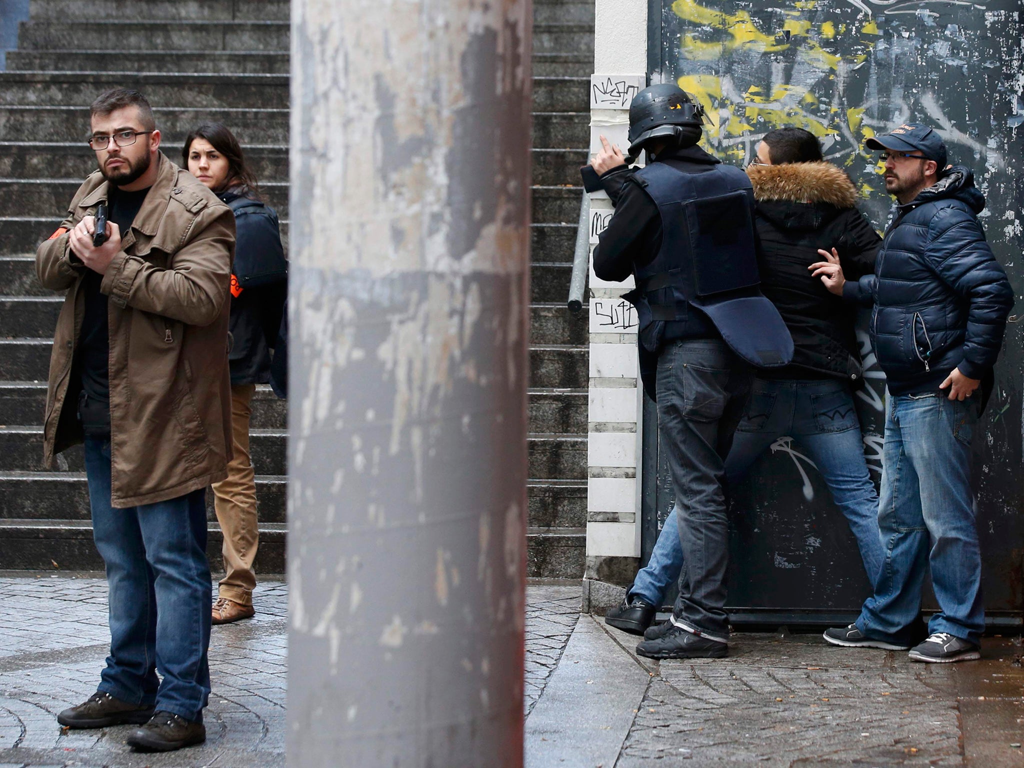 French police check a pedestrian as they secure the area after a man was shot dead at a police station in the 18th district in Paris