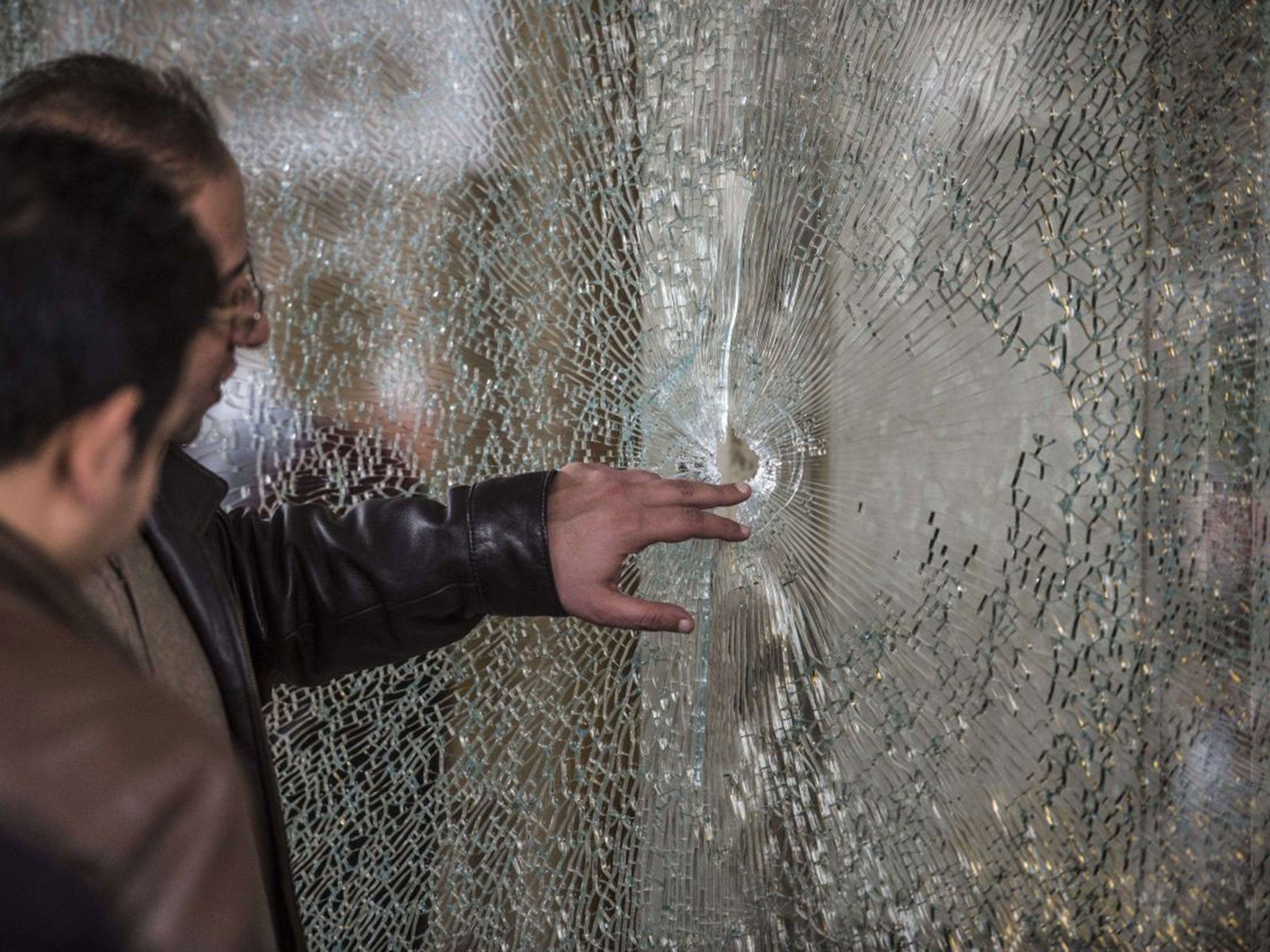 Egyptian forensic experts inspect a window at the entrance of the Three Pyramids hotel in Cairo's al-Harm district on January 7, 2016