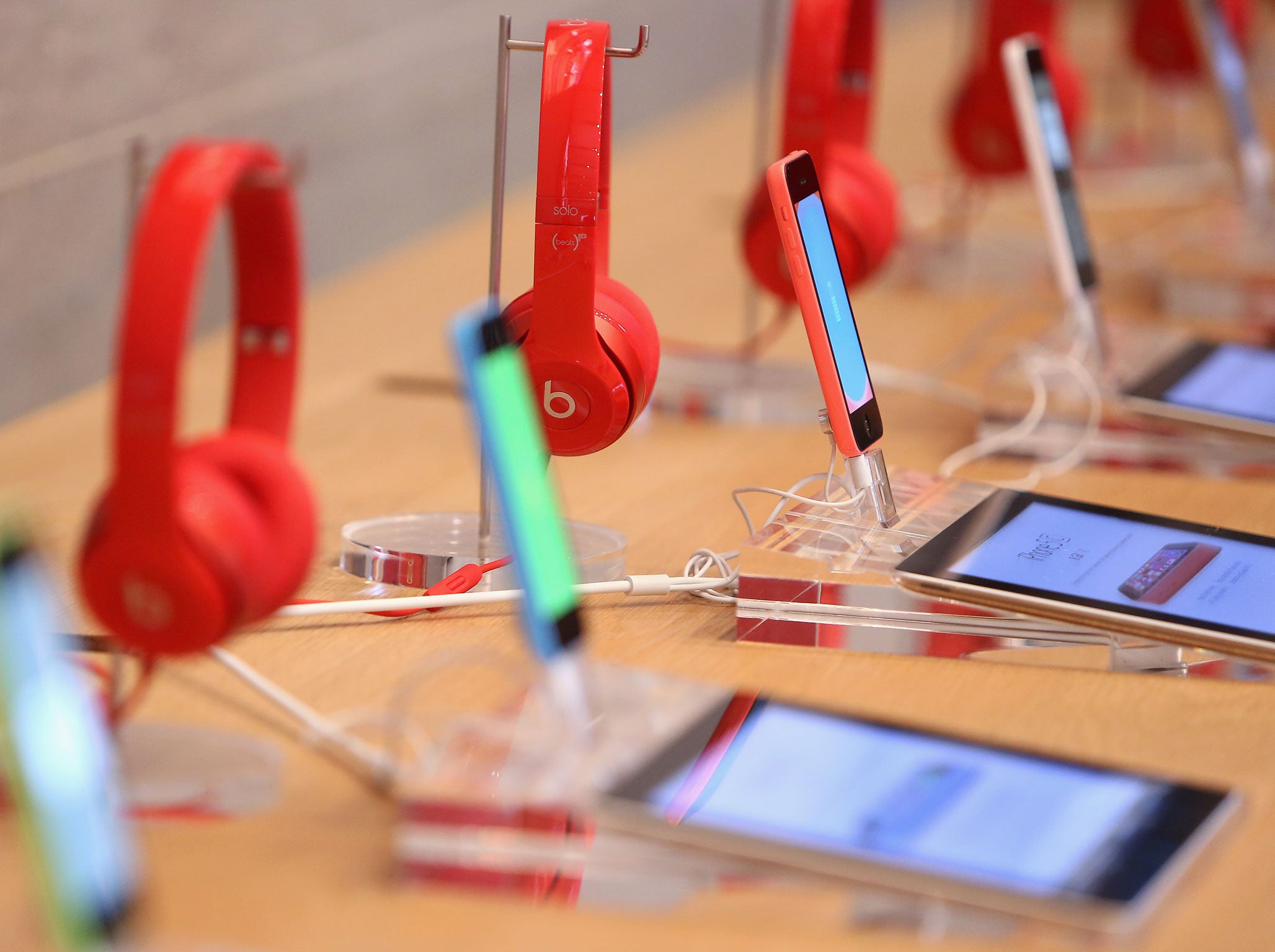 Red Beats by Dre headphones are seen on display behind iPads and iPhones at the Apple Store on December 1, 2014 in Berlin, Germany