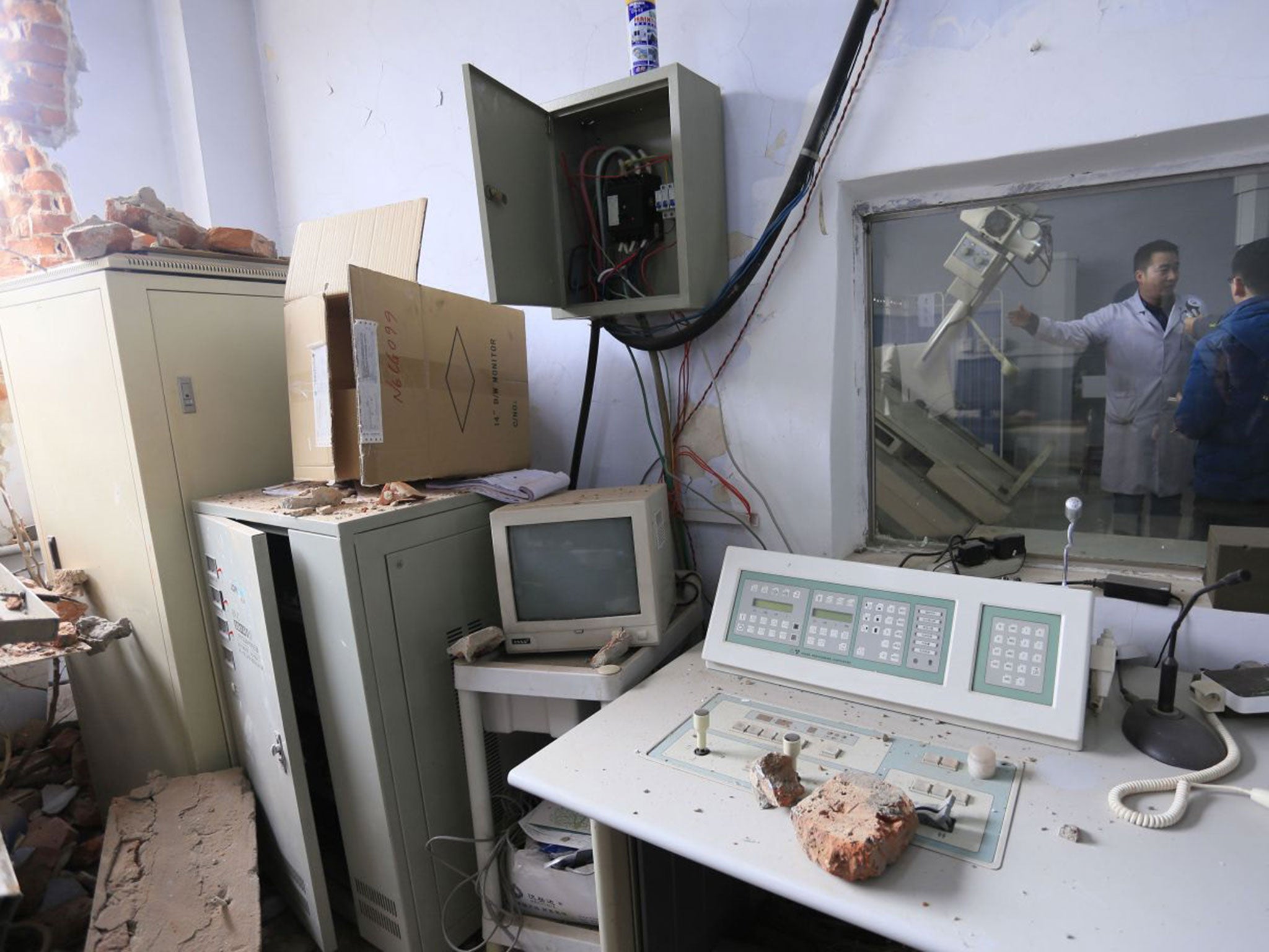 A doctor shows local press the aftermath of the bulldozing incident, including equipment torn off sockets and bricks strewn across the clinic