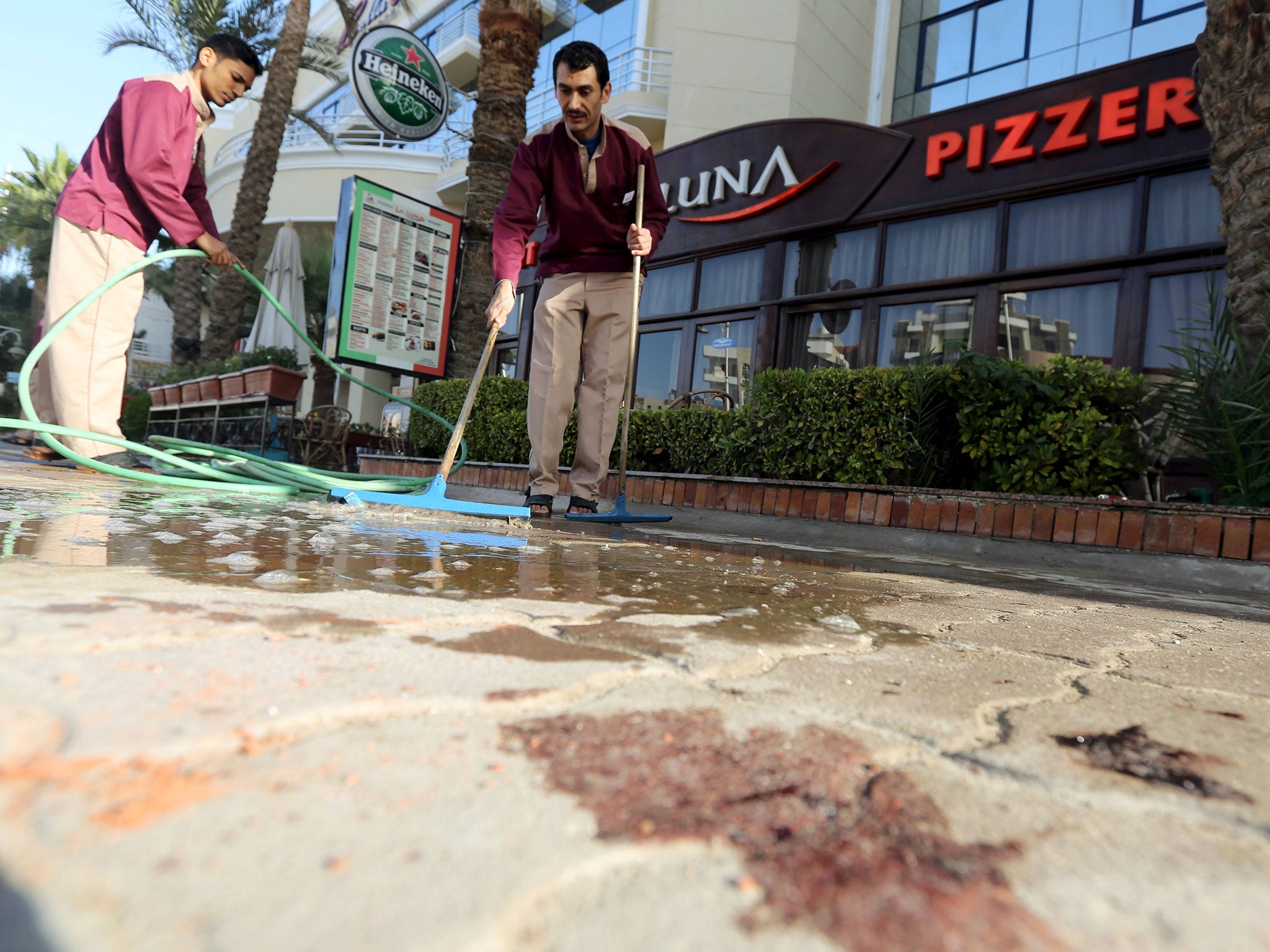 Cleaners try to clean blood stains near the entrance to Bella Vista Hotel in the Red Sea resort of Hurghada, Egypt, January 9, 2016