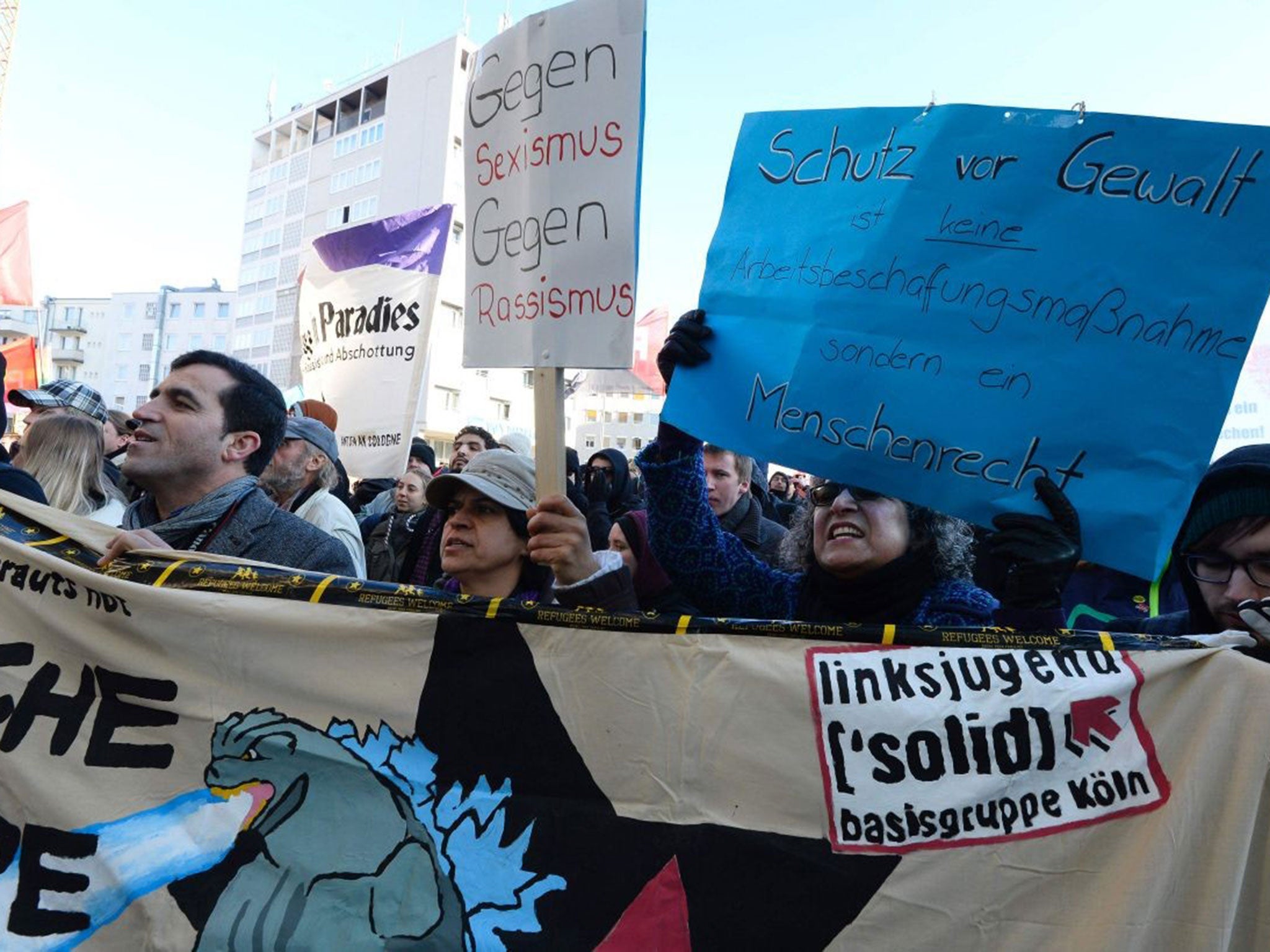 Counter demonstrators hold up a sign reading "Against sexism, against racism" as they protest against a demonstration of the islamophobic movement PEGIDA at the train station in Cologne, Germany, on January 9, 2016.