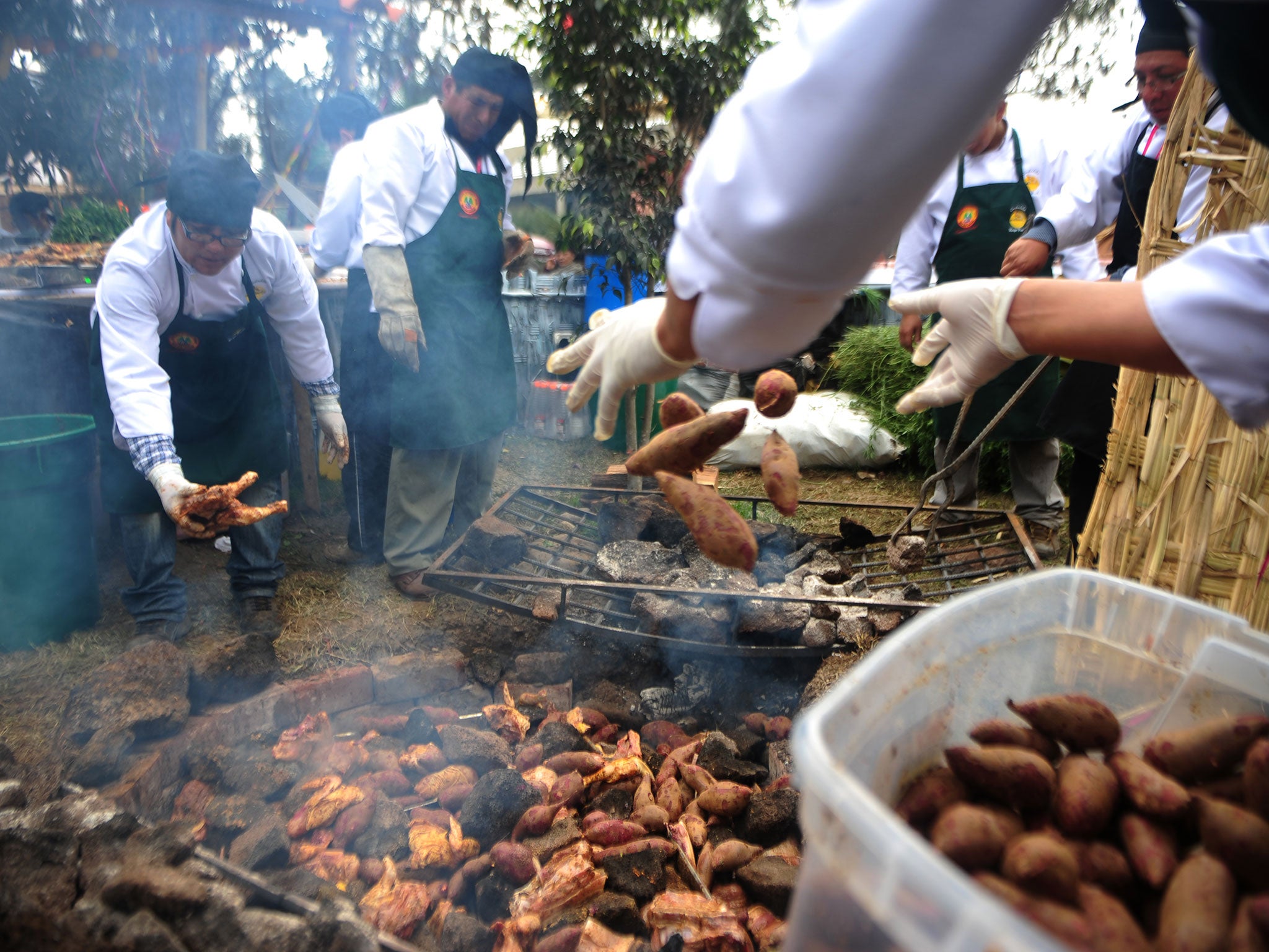 Cooks prepare a potato dish at a Lima food fair