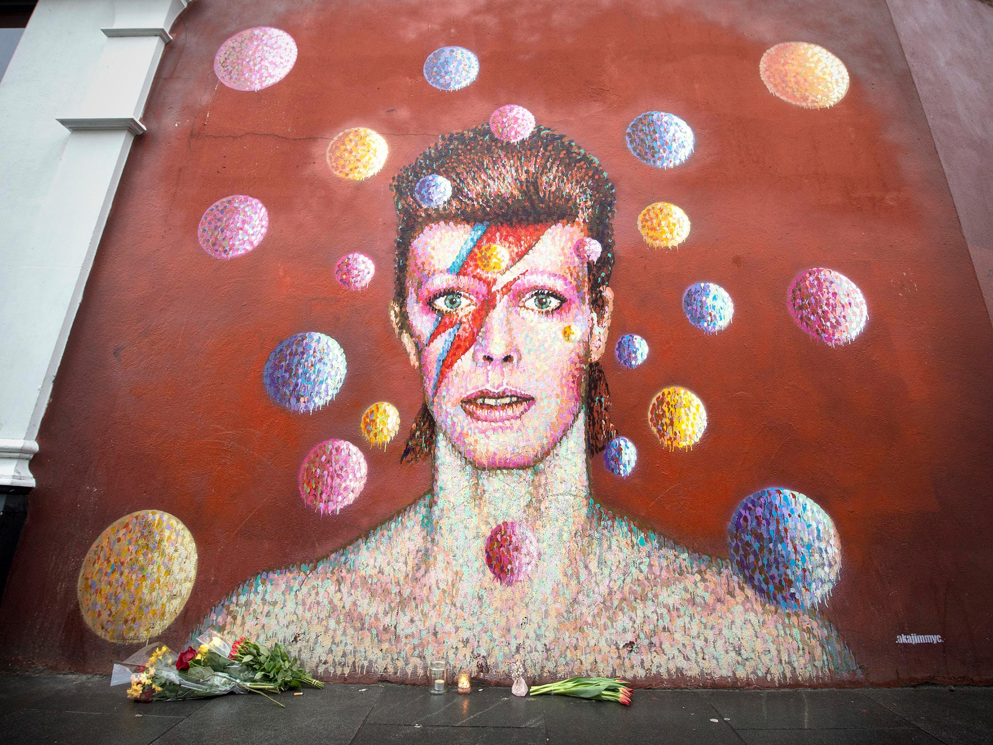 Flowers are left below a mural of David Bowie on the wall of a Morley's store in Brixton on 11 January 2016