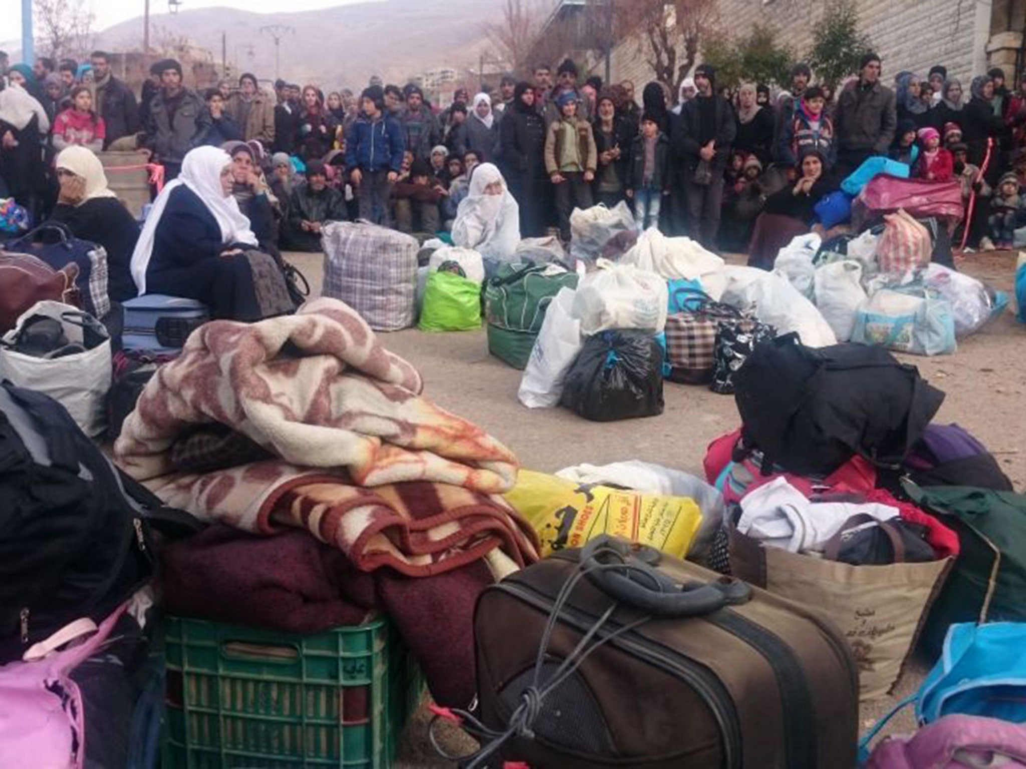 Residents of the town of Madaya wait for the UN aid convey after a six-month siege left them short of food