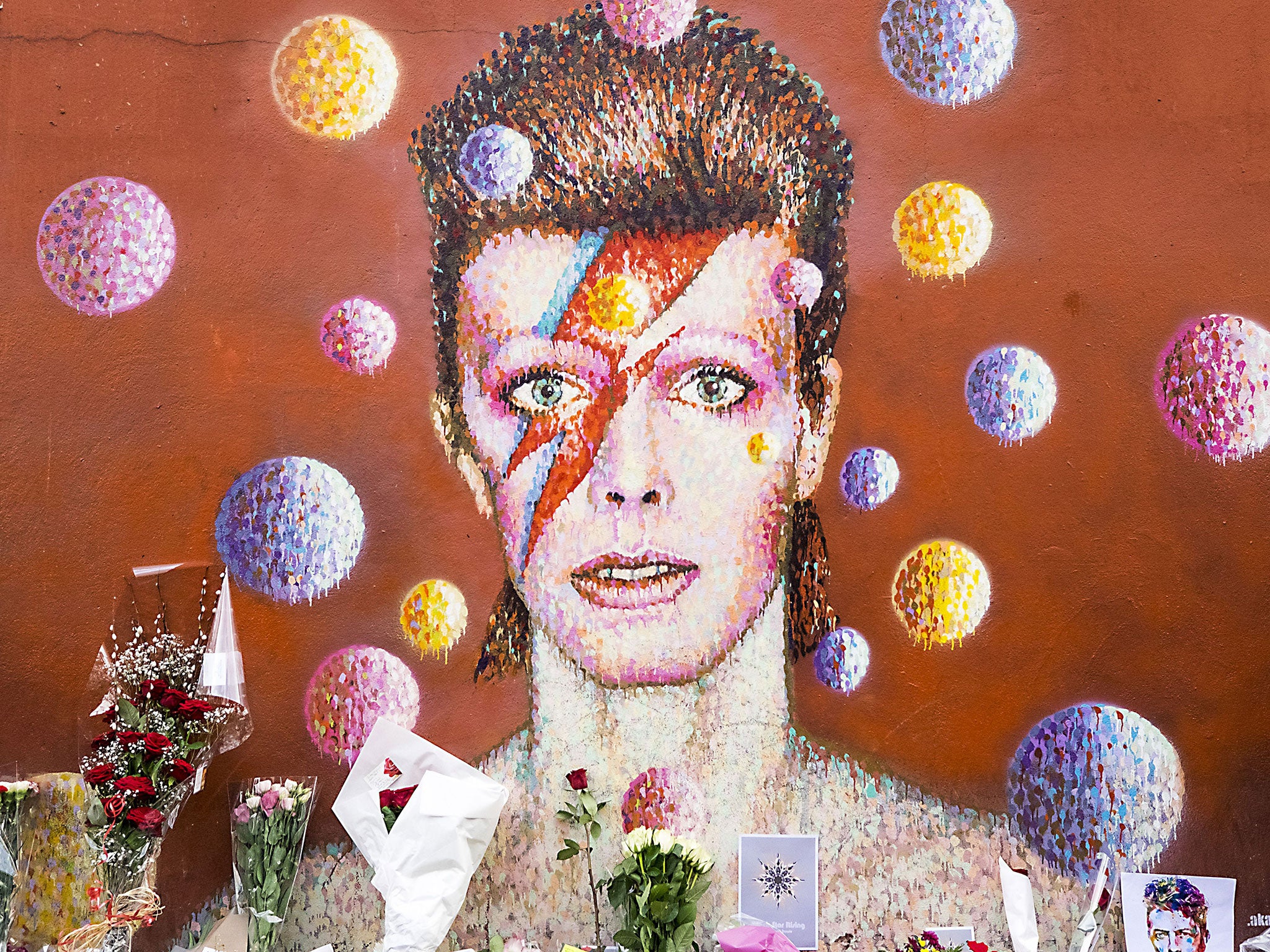 Tributes to David Bowie laid beneath a mural in Brixton, London