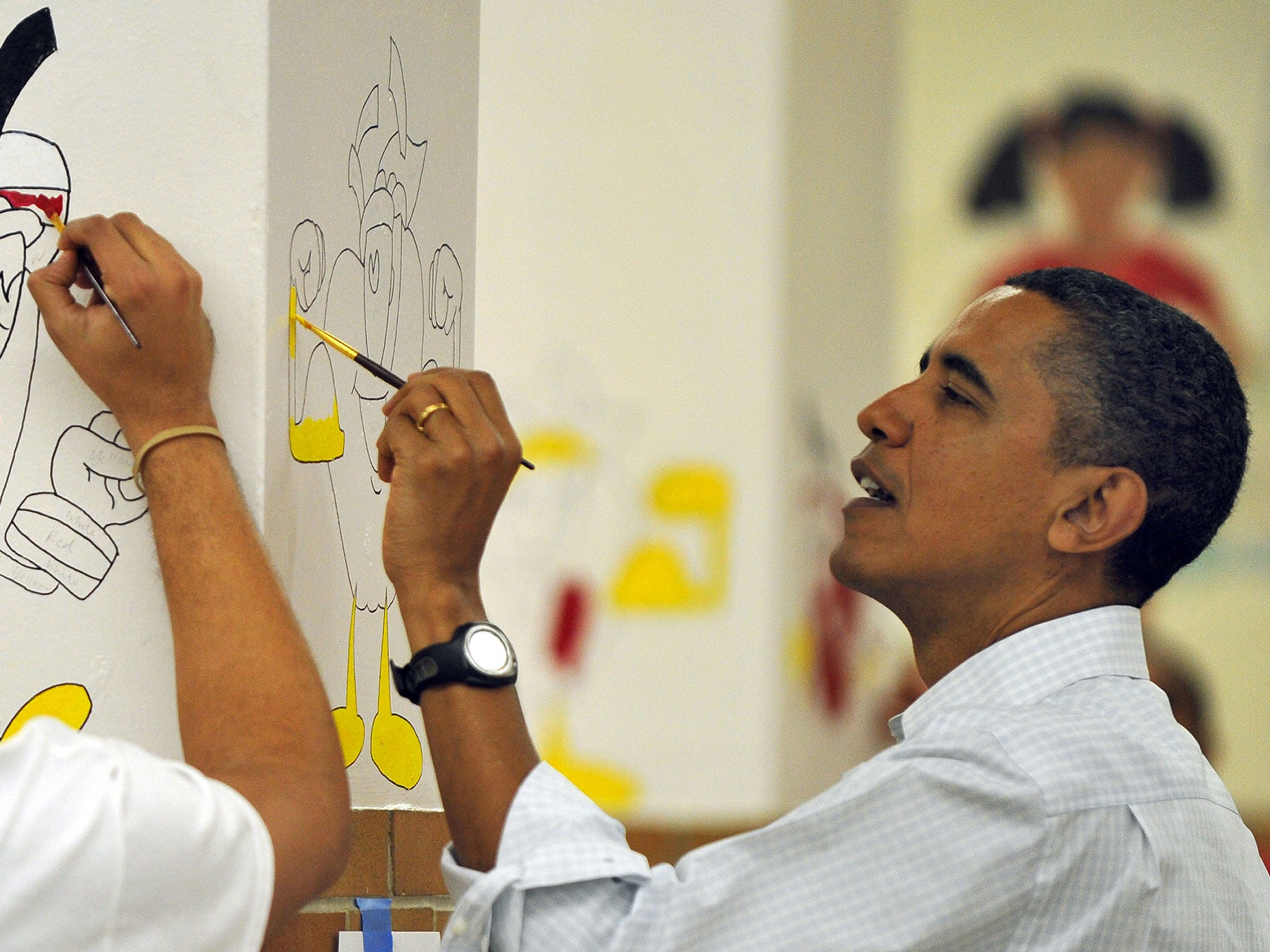 Barack Obama paints on a wall as part of a community service project for Martin Luther King Day