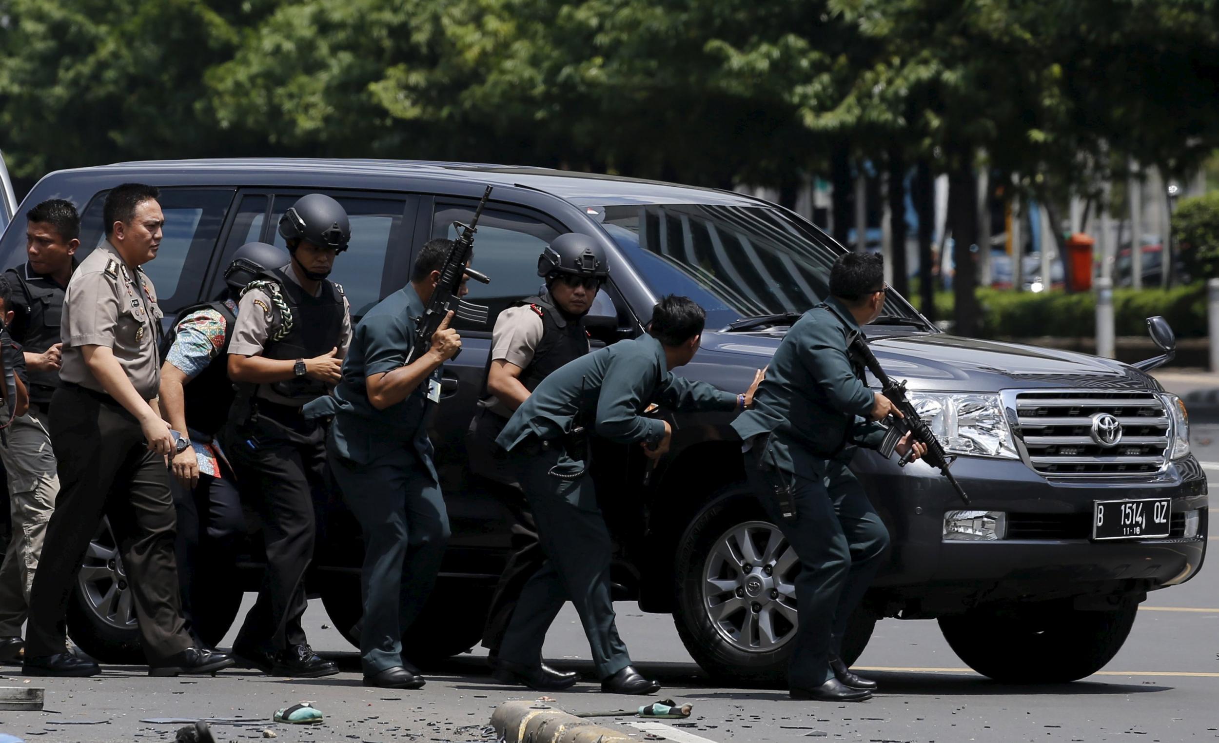 Police hold rifles while walking behind a car for protection