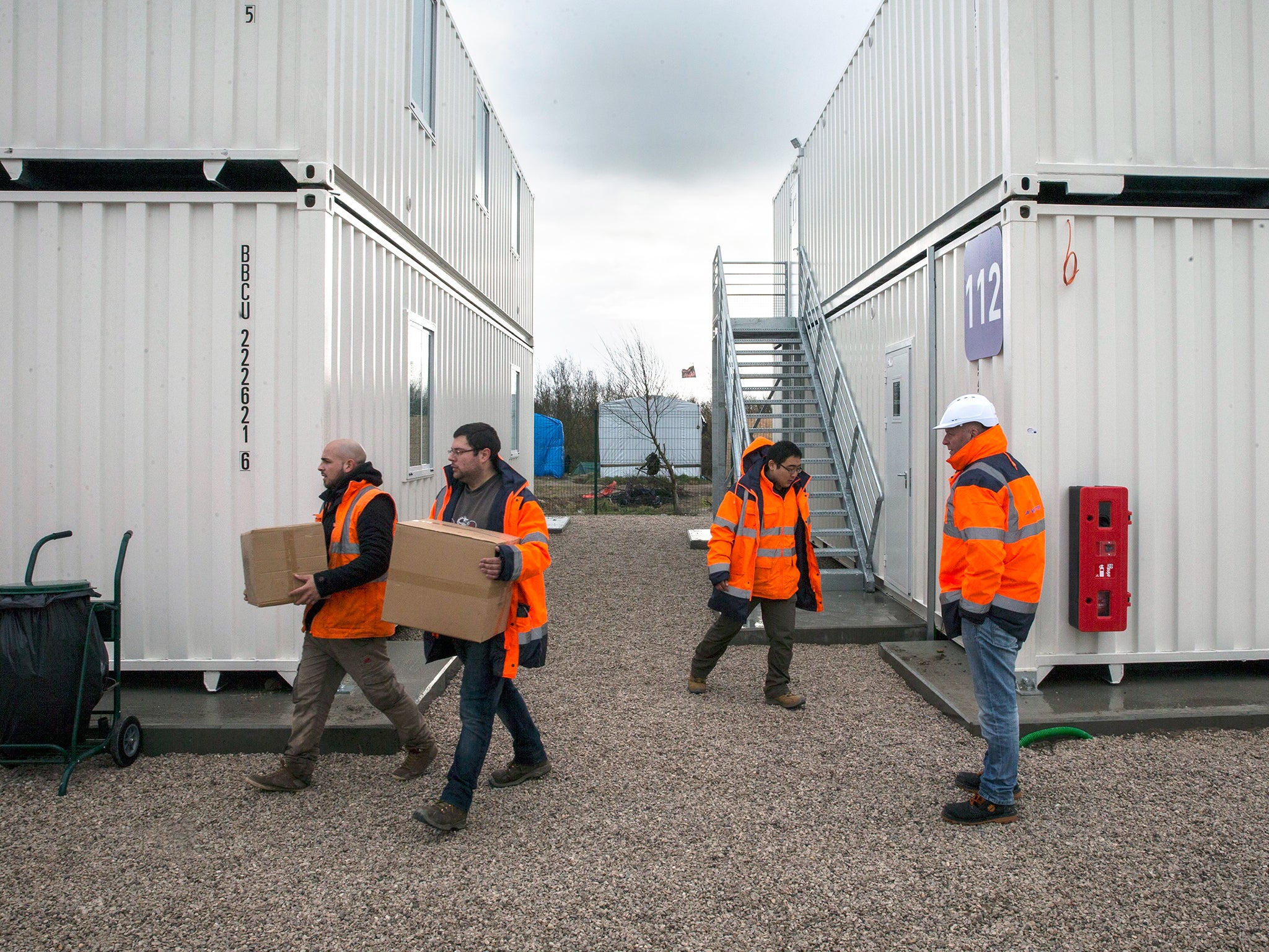 Volunteers work prior to the inauguration of the secured area of the makeshift migrant camp called 'The Jungle' where several containers were recycled into rooms in Calais