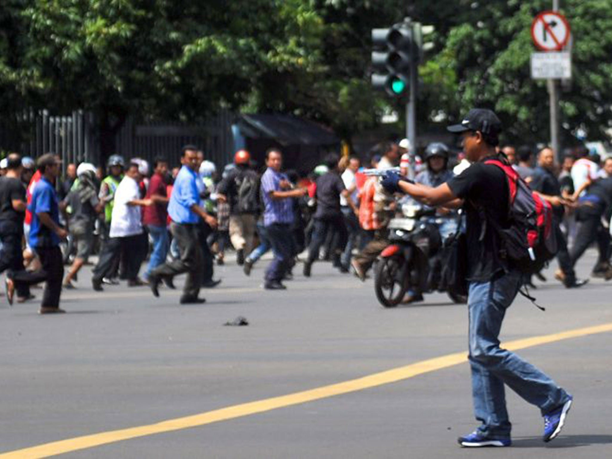 &#13;
Moment of terror... a man points a gun towards a crowd of people in central Jakarta &#13;