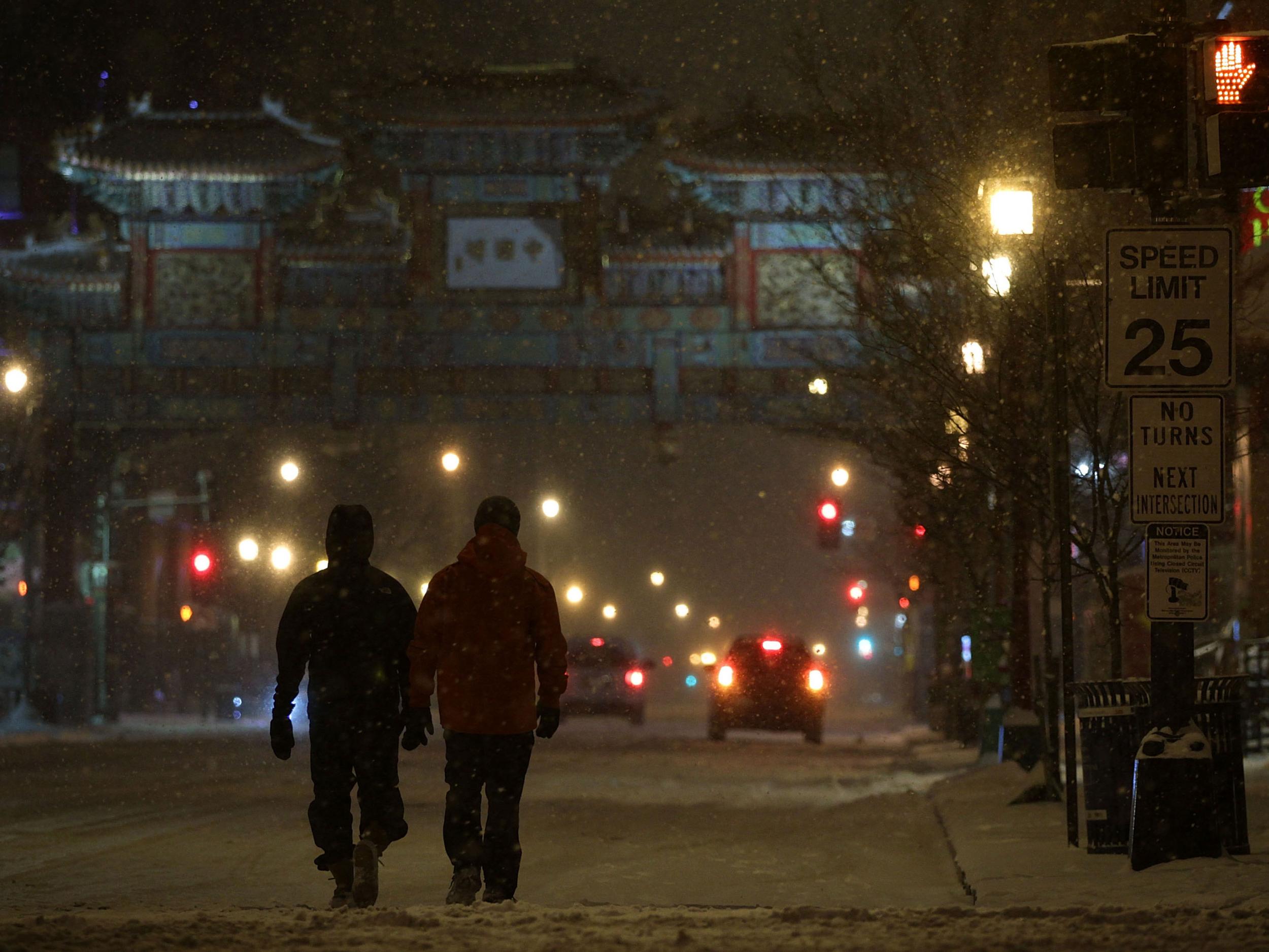 Pedestrians walk on H Street, Washington DC in the snow Getty