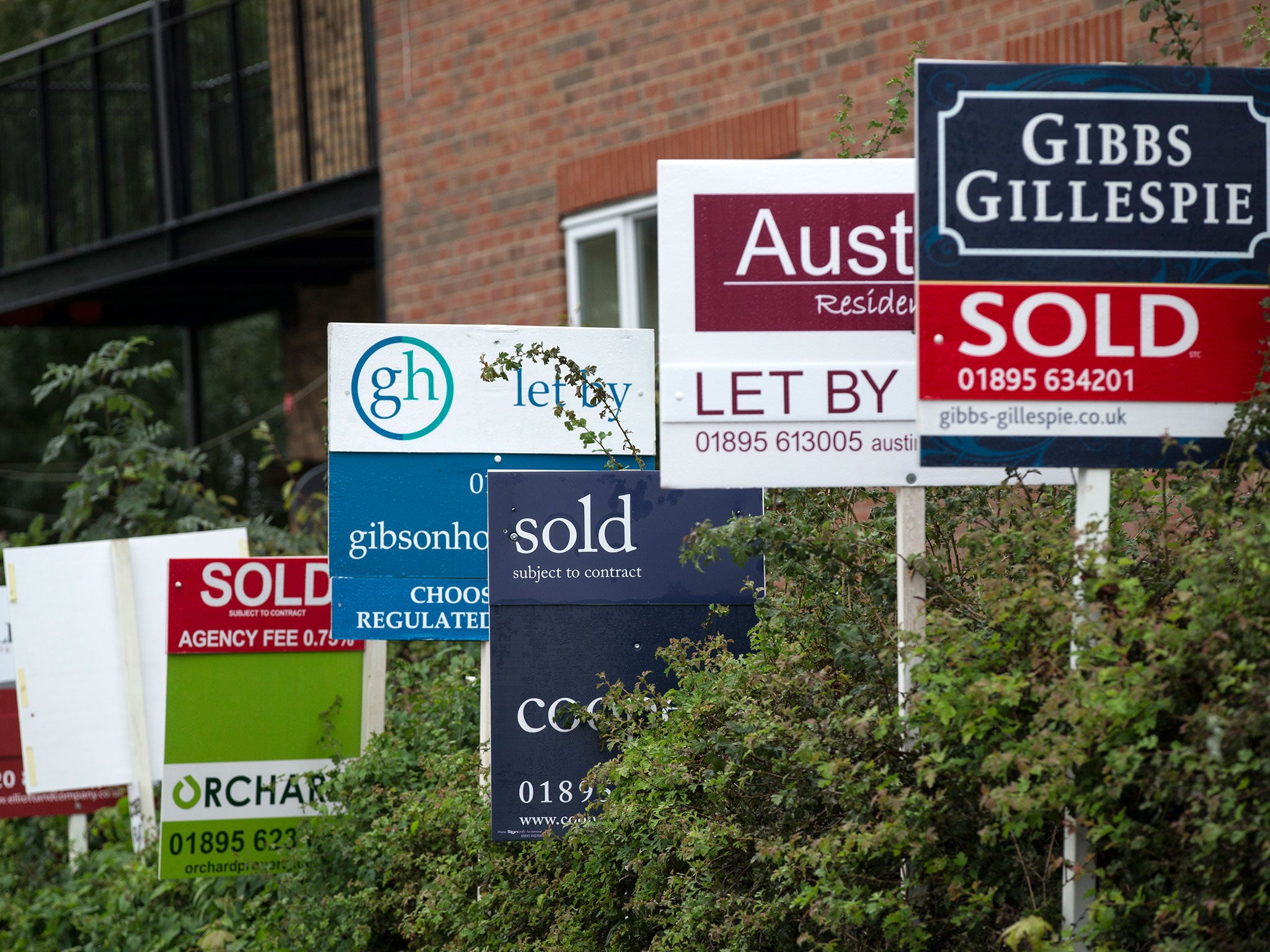 A row of estate agent boards are placed outside sold and let properties