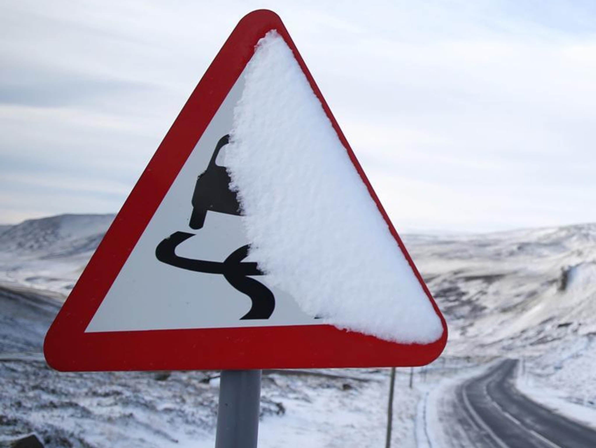 A slippery road warning sign is covered in snow on the A93 in Perthshire, Scotland