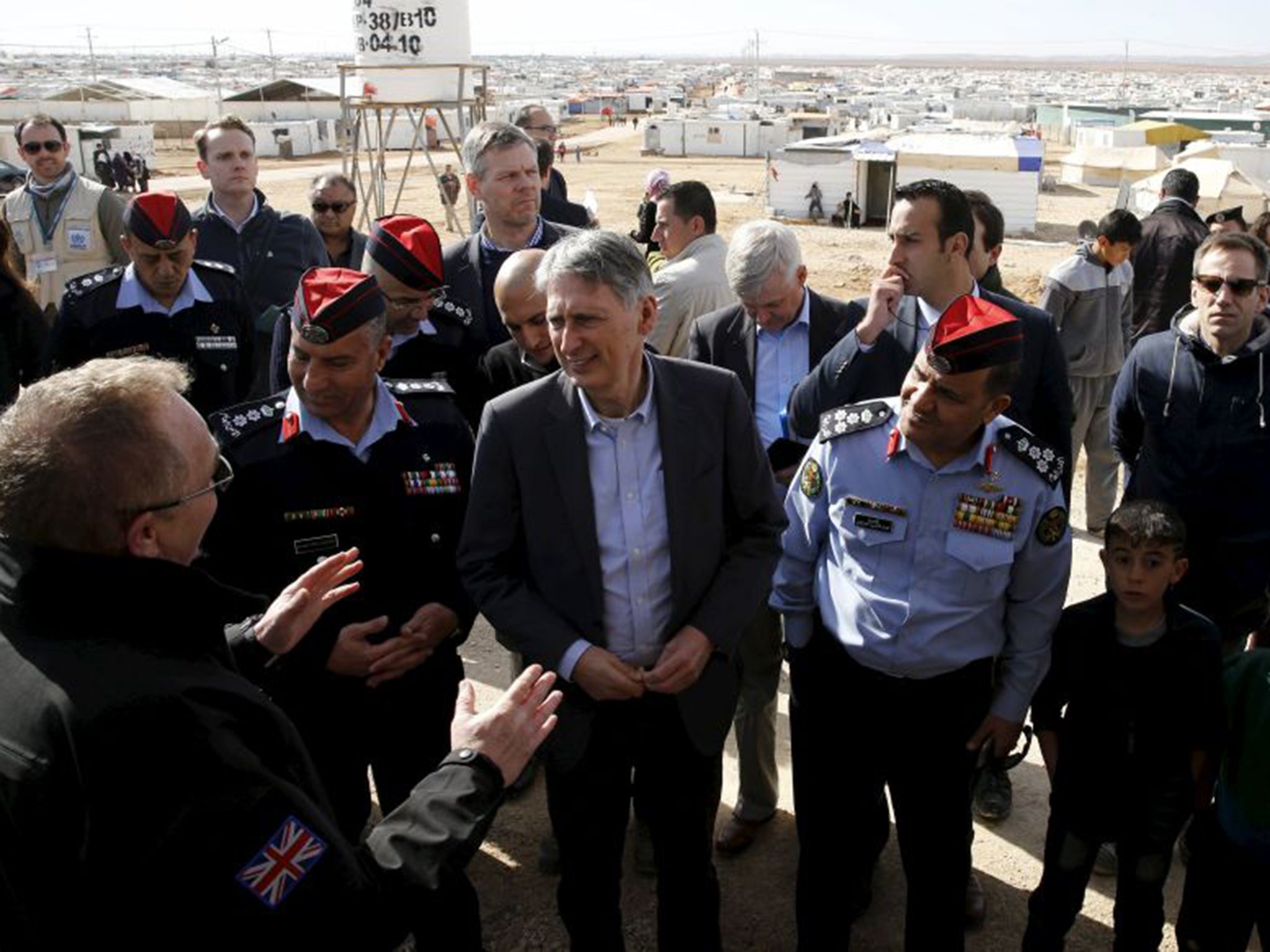 Foreign Secretary Philip Hammond, centre, speaks with former British police officers on his visit to the Zaatari refugee camp, now as large as a city