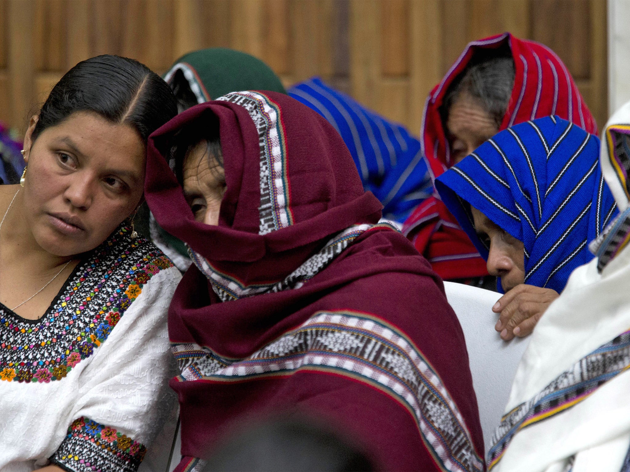 Alleged victims of sexual violence cover their faces as they listen to an interpreter on the first day of a trial against two former soldiers