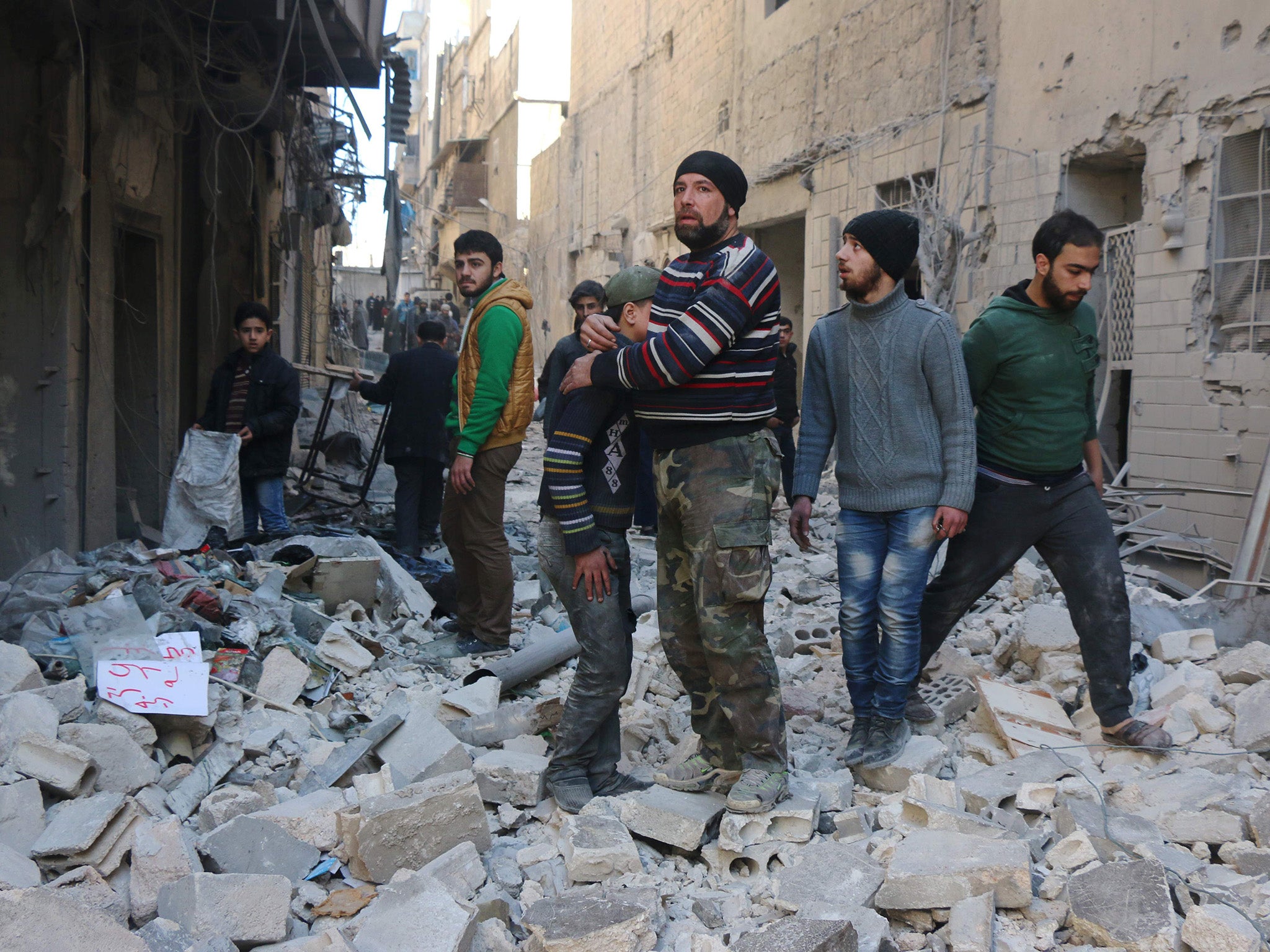 A Syrian man comforts a boy amid the rubble of buildings following a reported air strike on the rebel-held neighbourhood of al-Kalasa in the northern Syrian city of Aleppo.