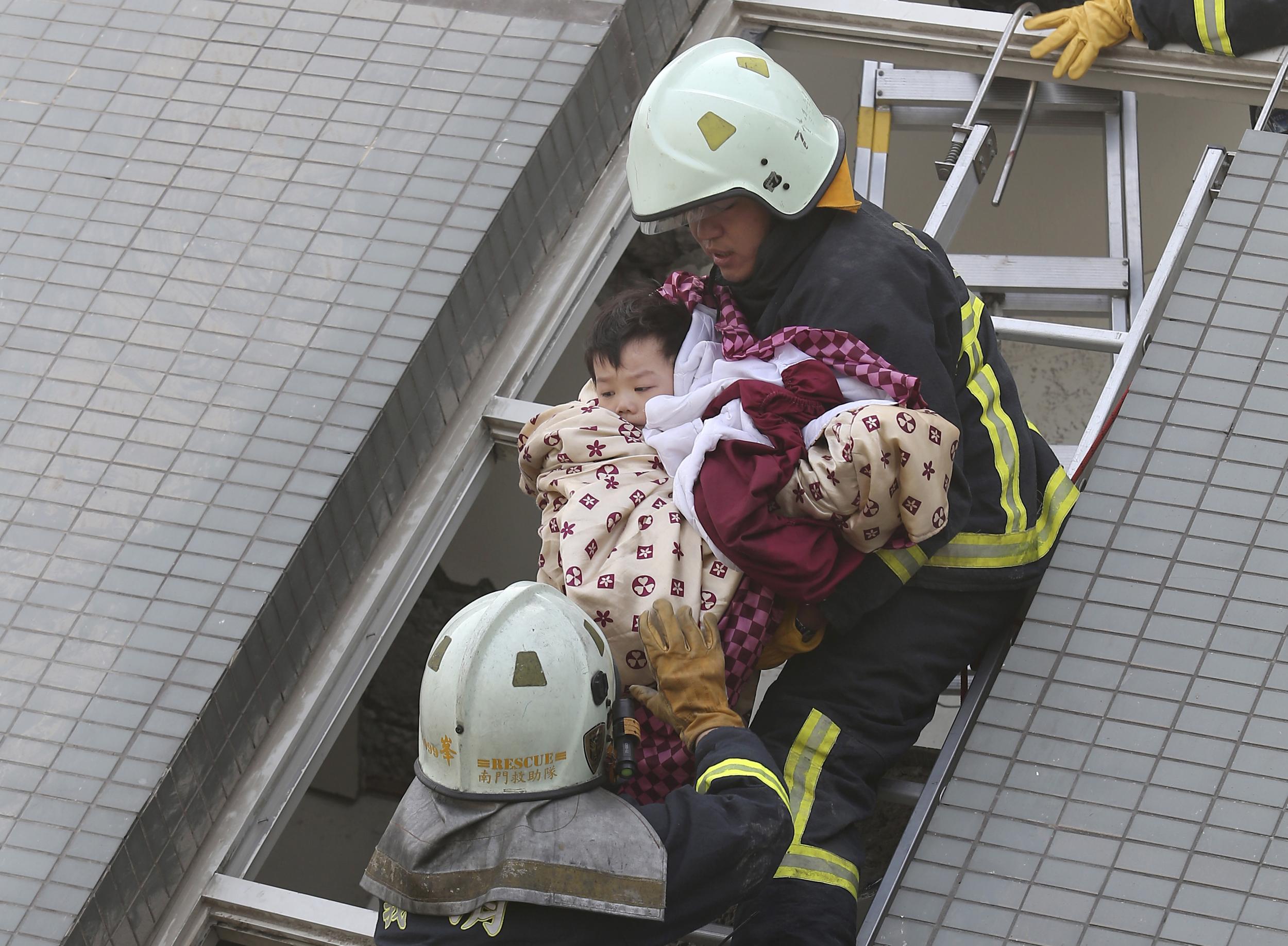 Another swaddled toddler being rescued from the collapsed residential complex