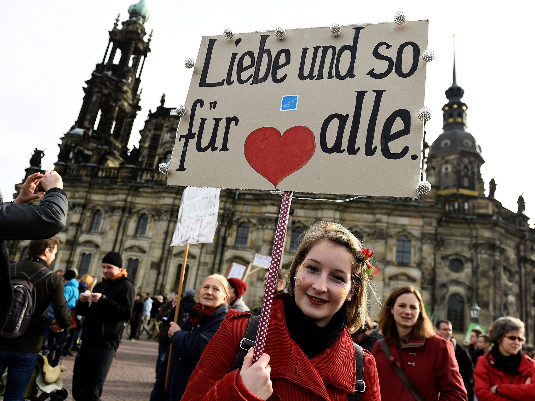 People gather in Dresden to protest against a mass rally of the Pegida movement with a placard reading 'Love for all' on February 6, 2016