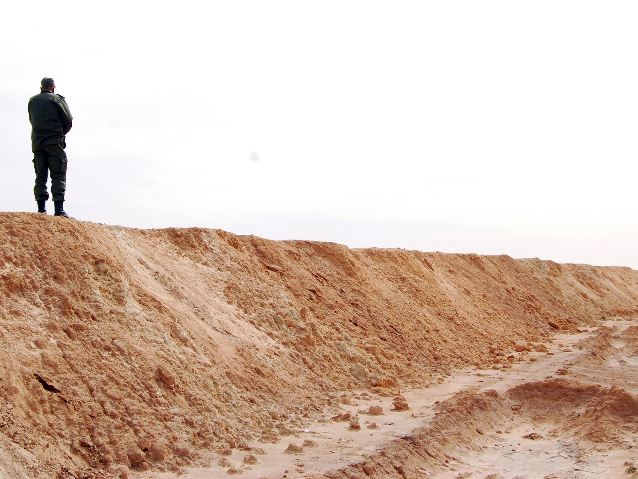 A Tunisian soldier stands on the partially-completed barrier