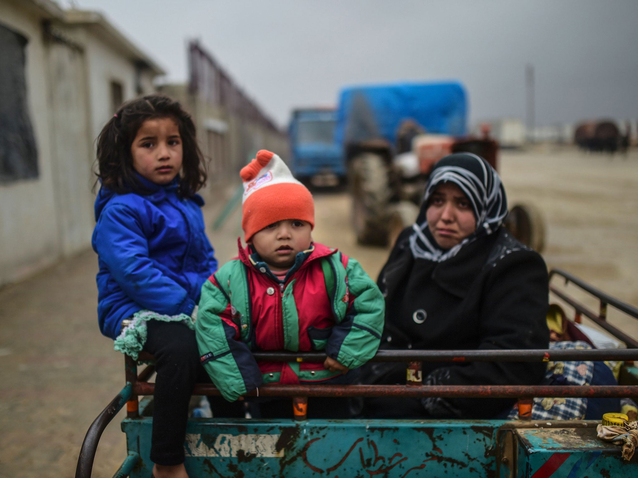 A refugee family, fleeing airstrikes in Aleppo, arrive at the Turkish border crossing of Bab-al Salam