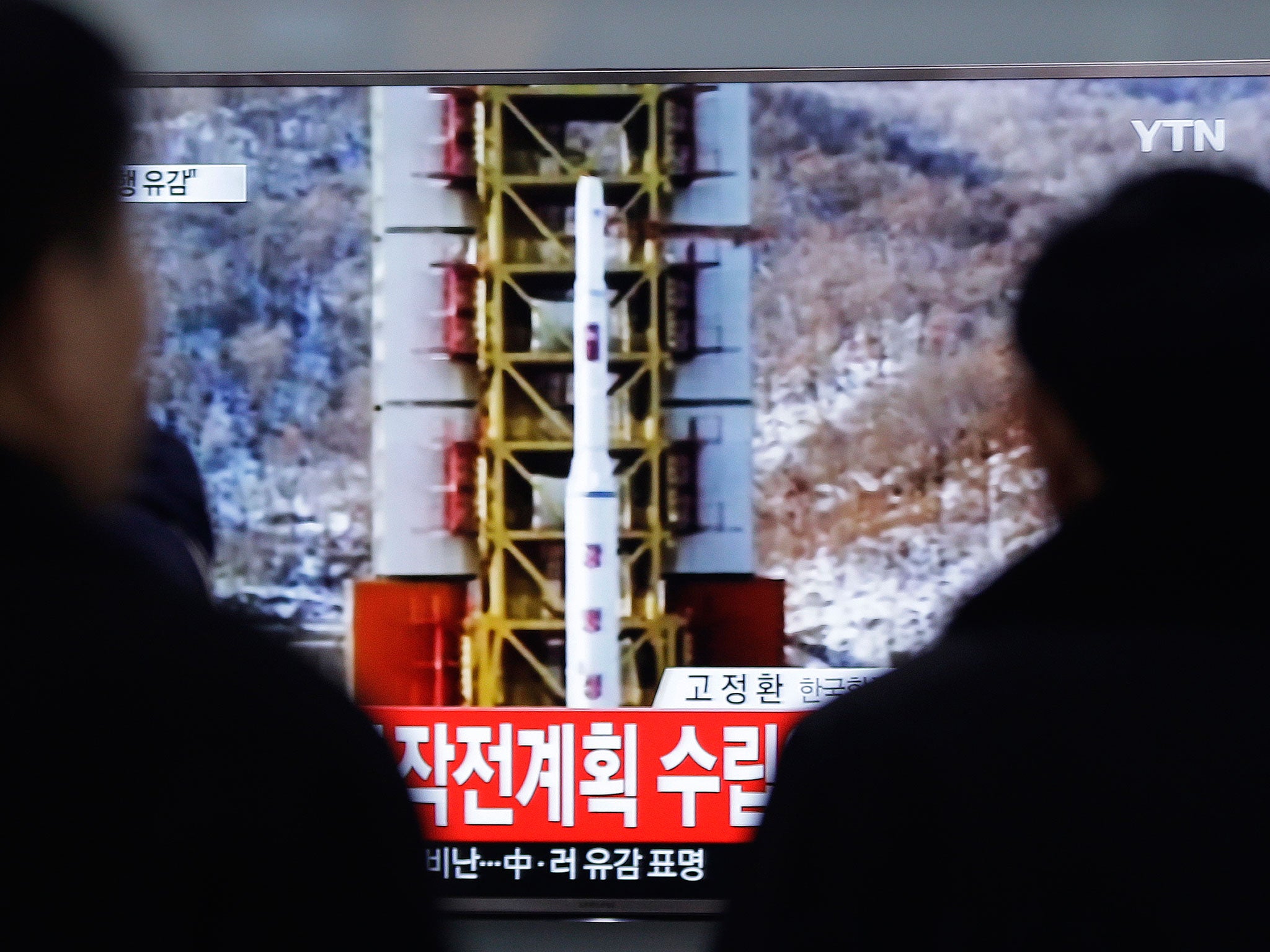 People watch a TV news reporting a rocket launch in North Korea, at Seoul Railway Station in Seoul