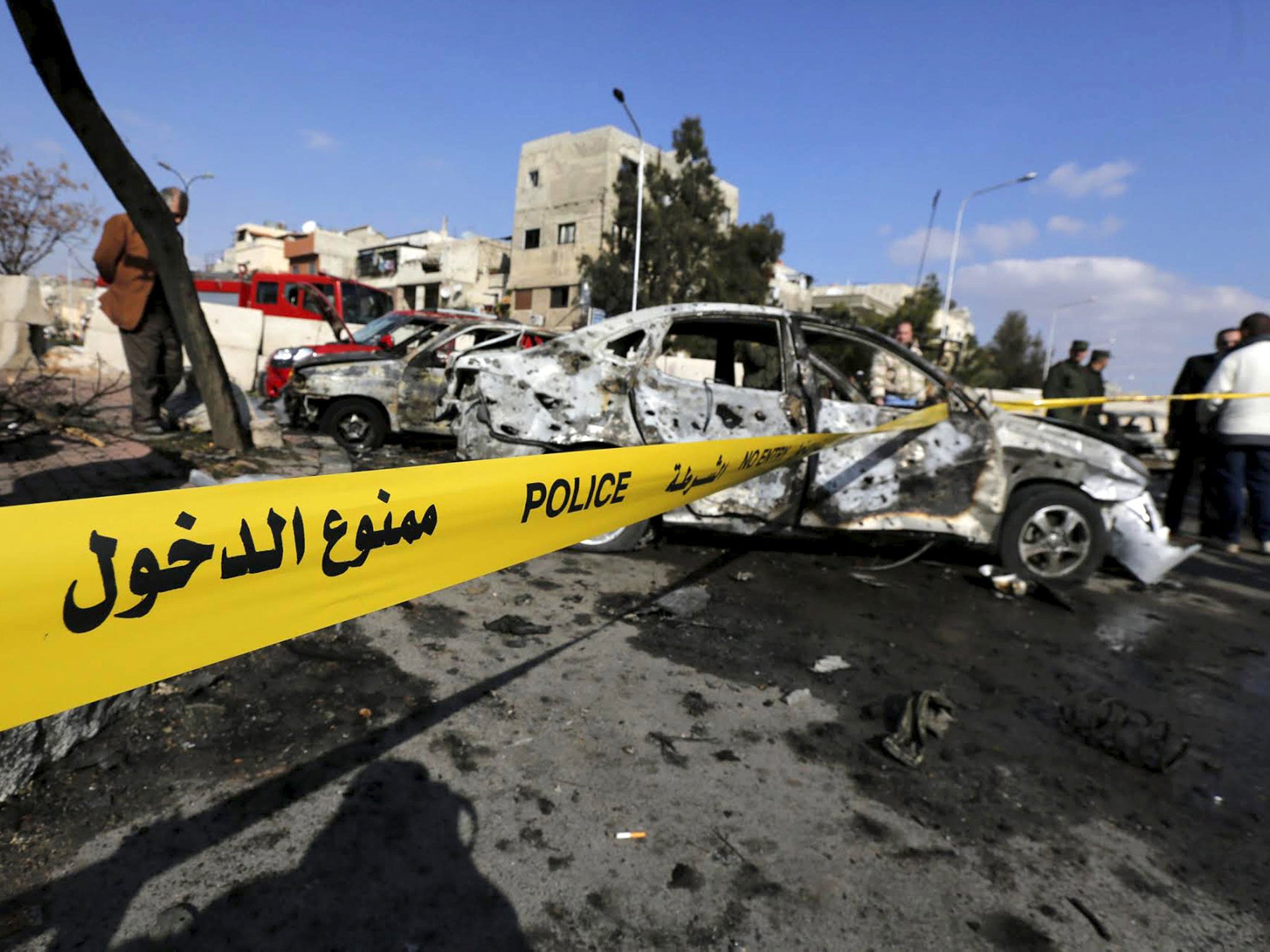 Syrian army soldiers and civilians inspect the site of a suicide bombing at a police officers' club in a residential district of Damascus