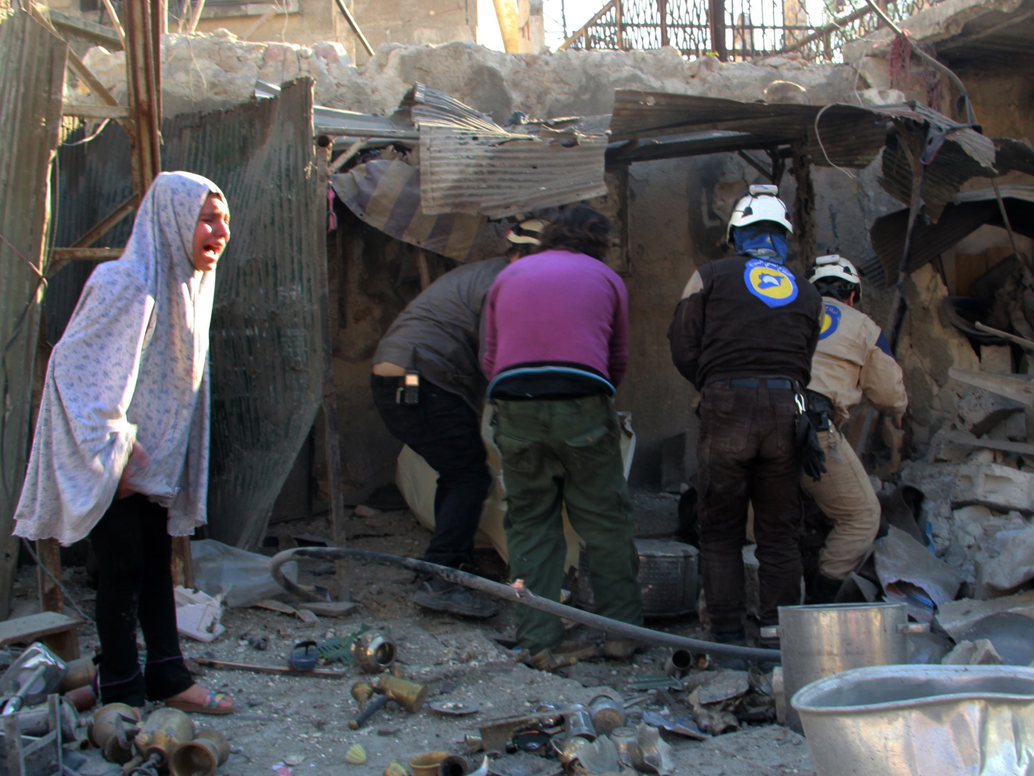 A Syrian girl whose home was destroyed by Russian airstrikes on Aleppo watches as workers attempt to clear away the rubble to look for survivors