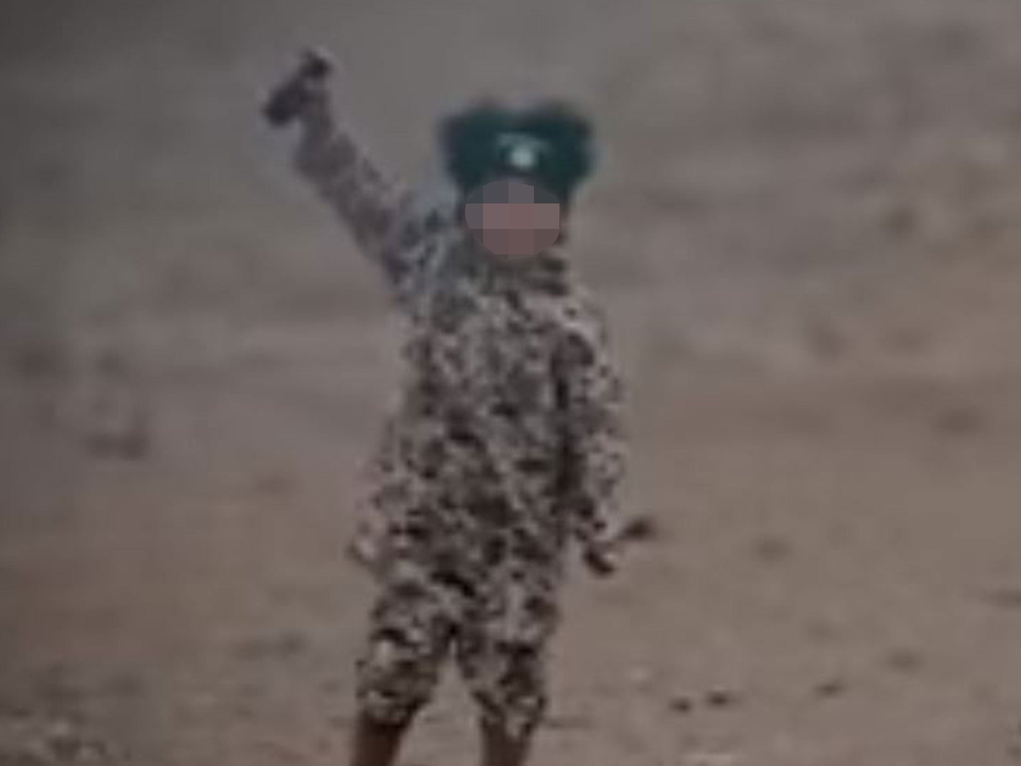 The boy is pictured with a detonator next to a burnt out wreckage