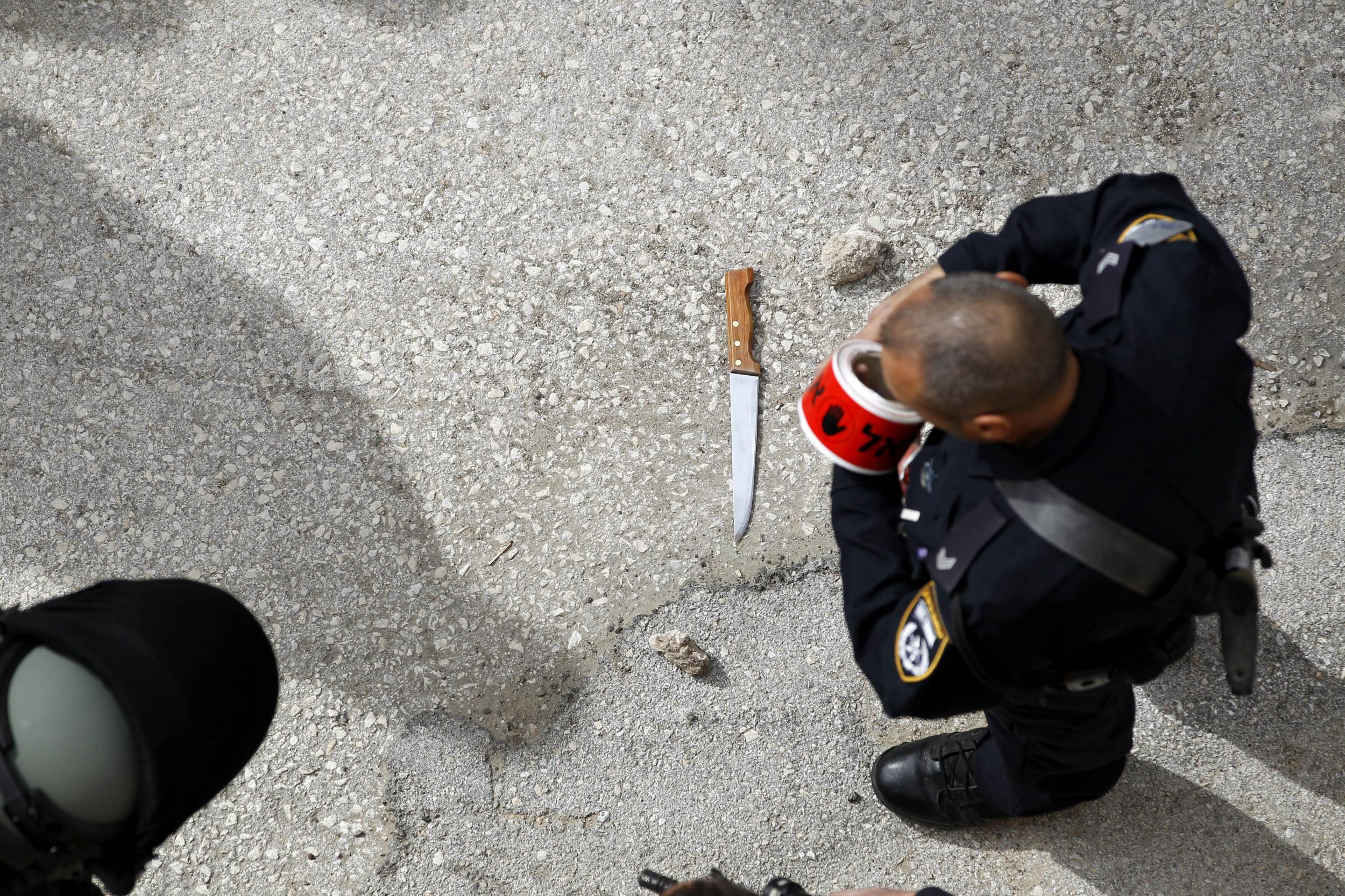 Israeli policeman looks down on a knife seen at scene of shooting in Hebron