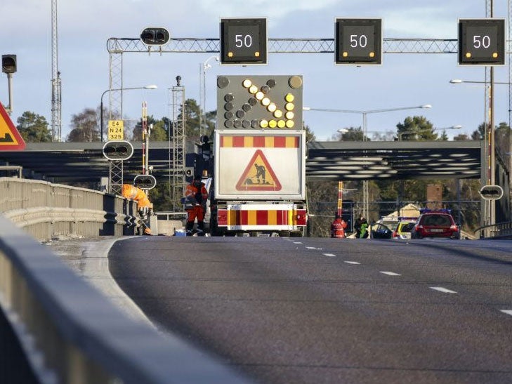 Service personnel repairing the gate a car drove through before crashing into the canal under the E4 highway bridge in Sodertalje, Sweden