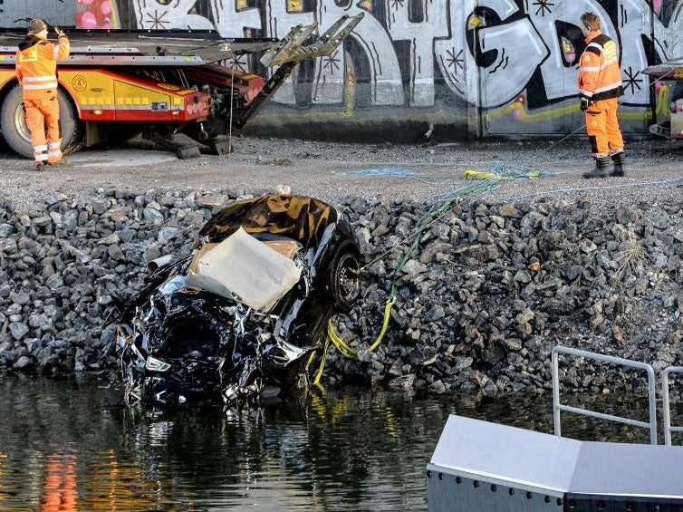 A badly damaged car is towed up from the canal under the E4 highway bridge in Sodertalje, Sweden Reuters