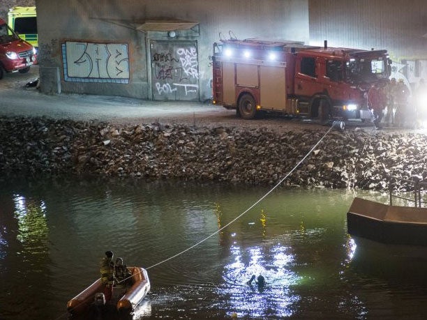 Divers and rescue service personnel search for the victims of the deadly car crash in the canal under the E4 highway bridge AP