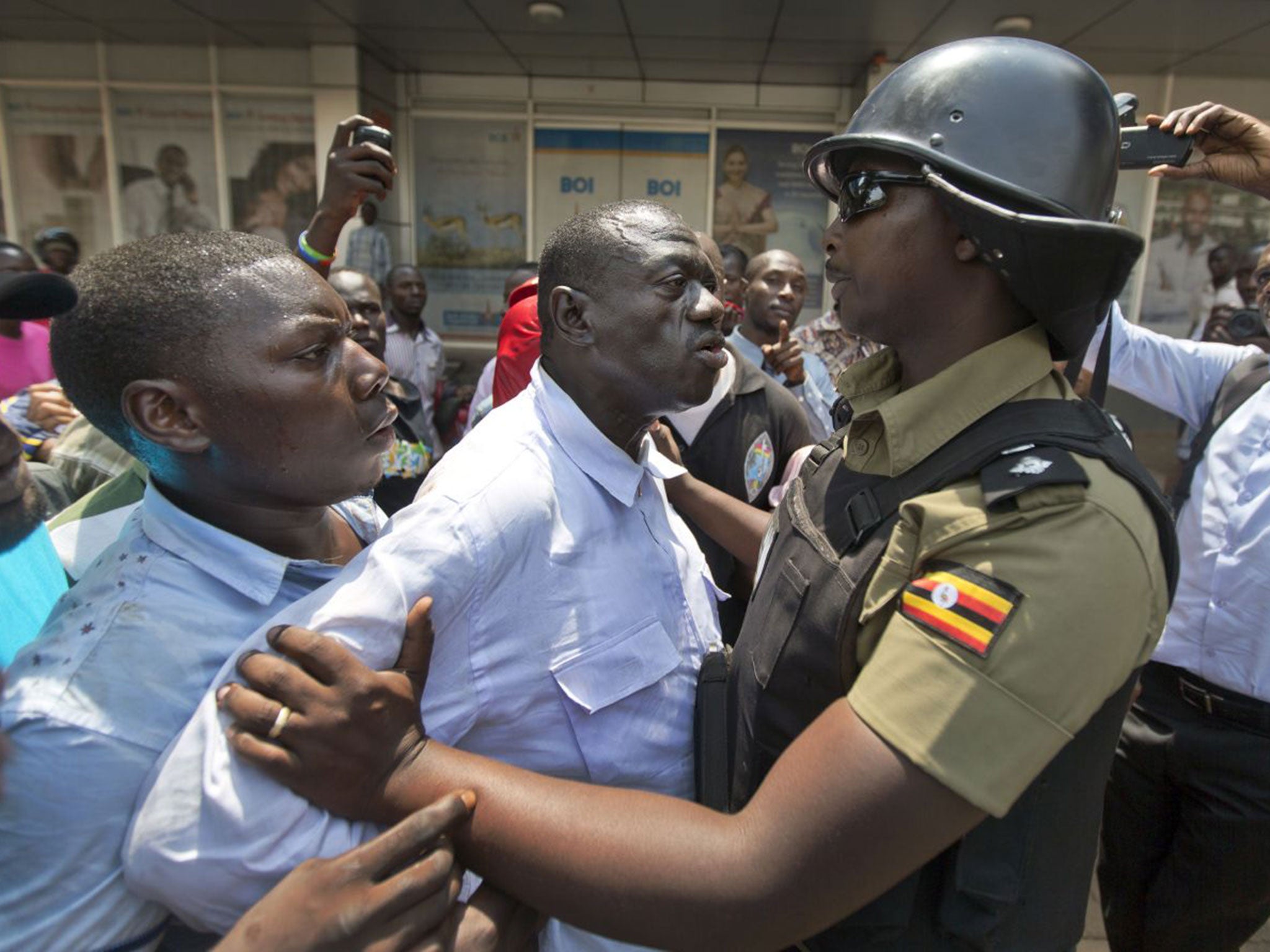 Presidential candidate Kizza Besigye, centre, is held by riot police after attempting to walk with his supporters along a street in Kampala yesterday. The rally was tear-gassed and Mr Besigye arrested