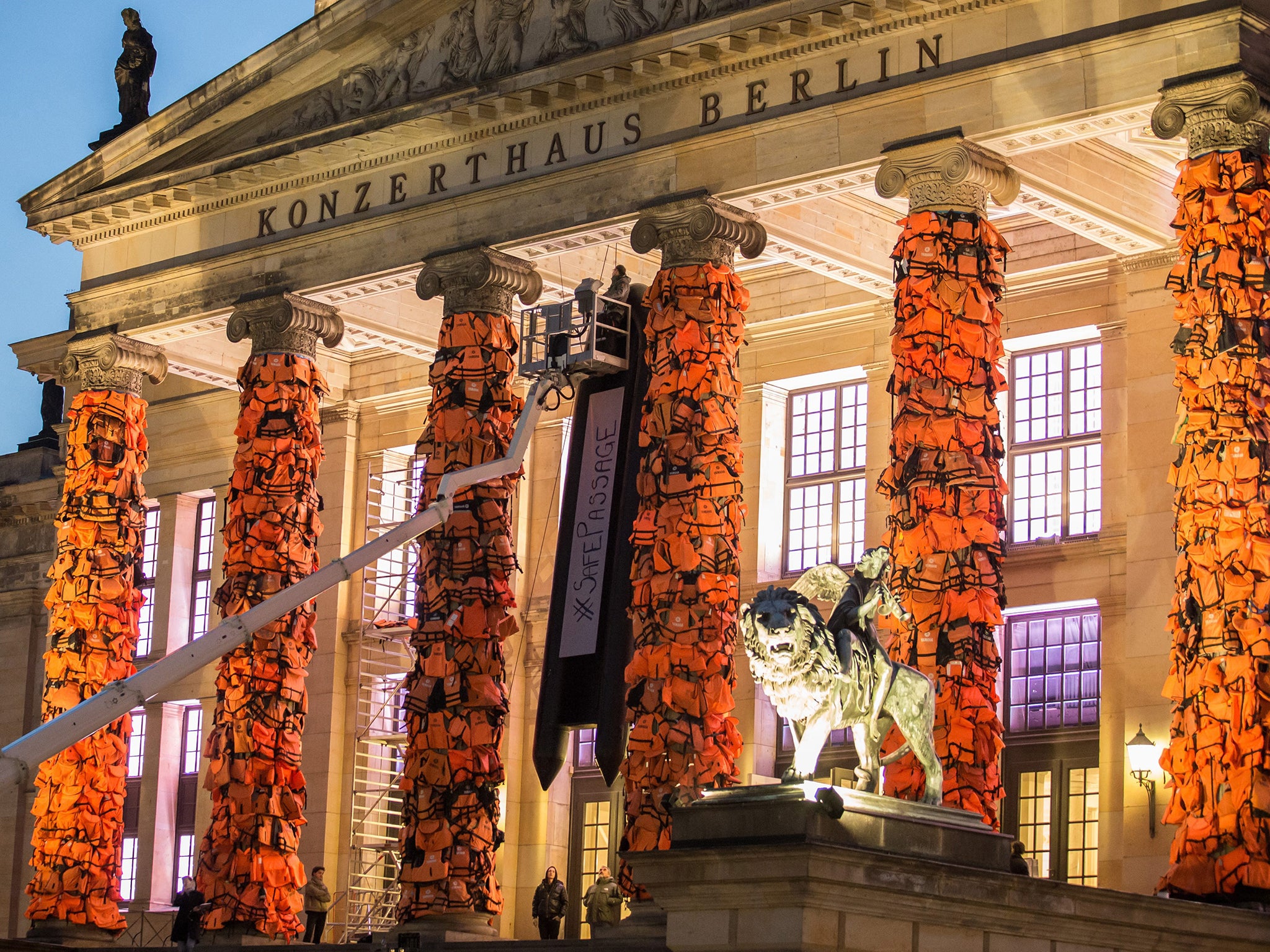 Workers attach life jackets used by refugees to the facade of the Berlin Concert Hall