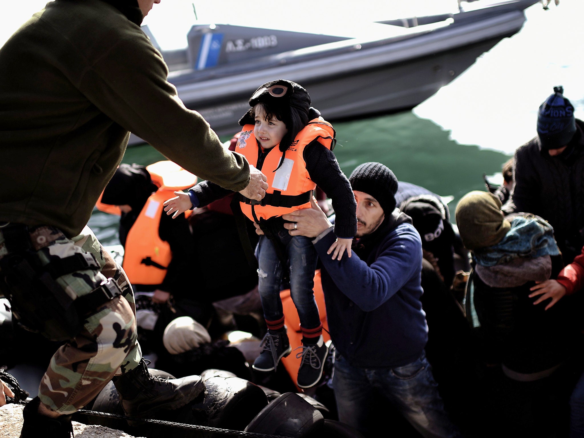 A Greek coastguard helps a migrant child to disembark, at the port of Mytilene, on the Greek island of Lesbos after crossing the Aegean sea from Turkey