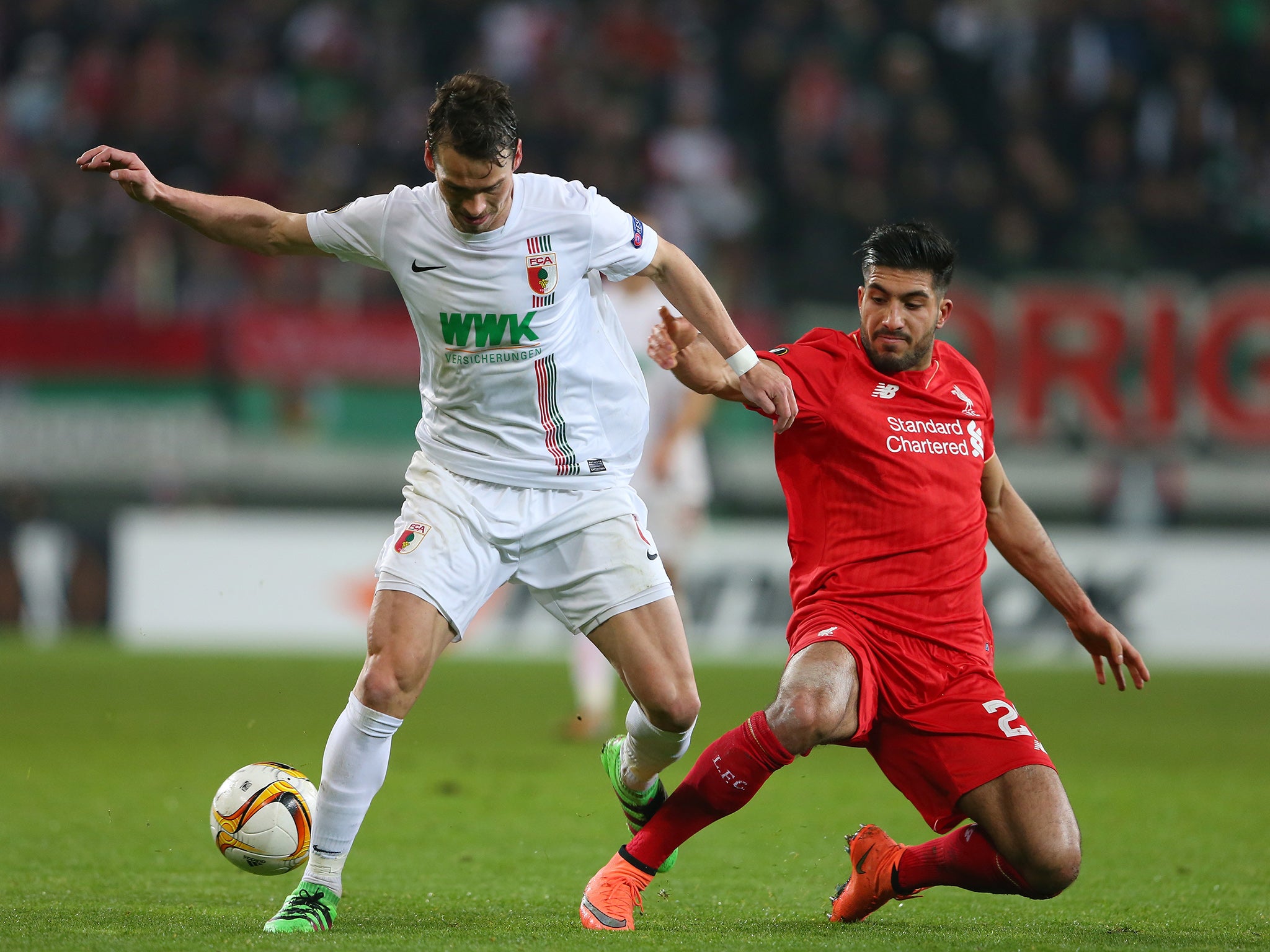 Augsburg's Markus Feulner competes for the ball with Liverpool's Emre Can