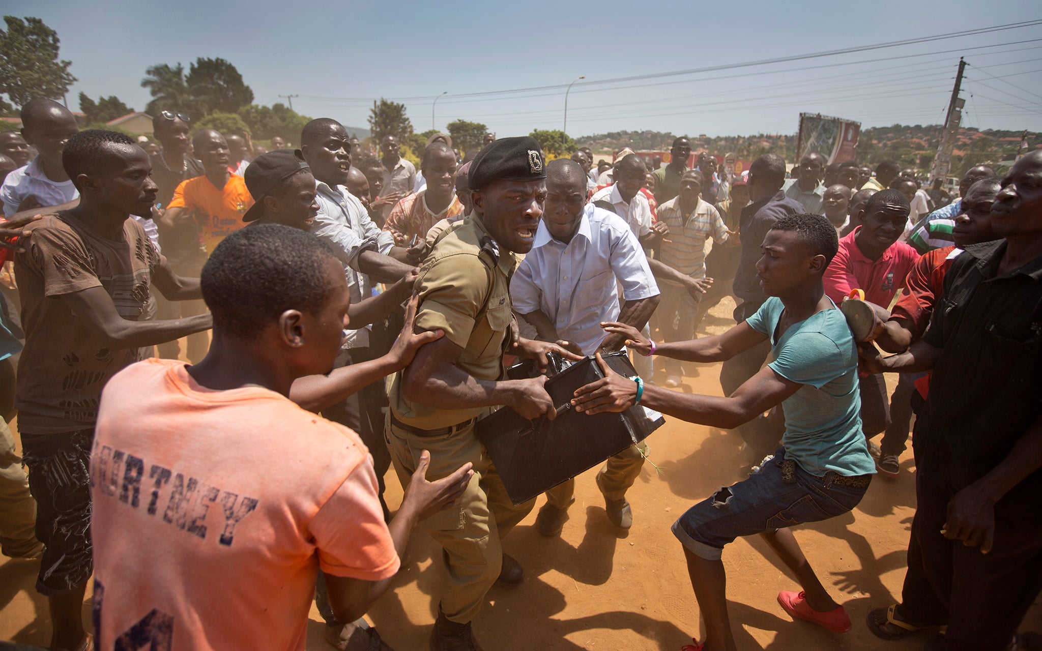 A police officer holding of a box containing voting materials, as voters surround him after waiting over 7 hours without being able to vote