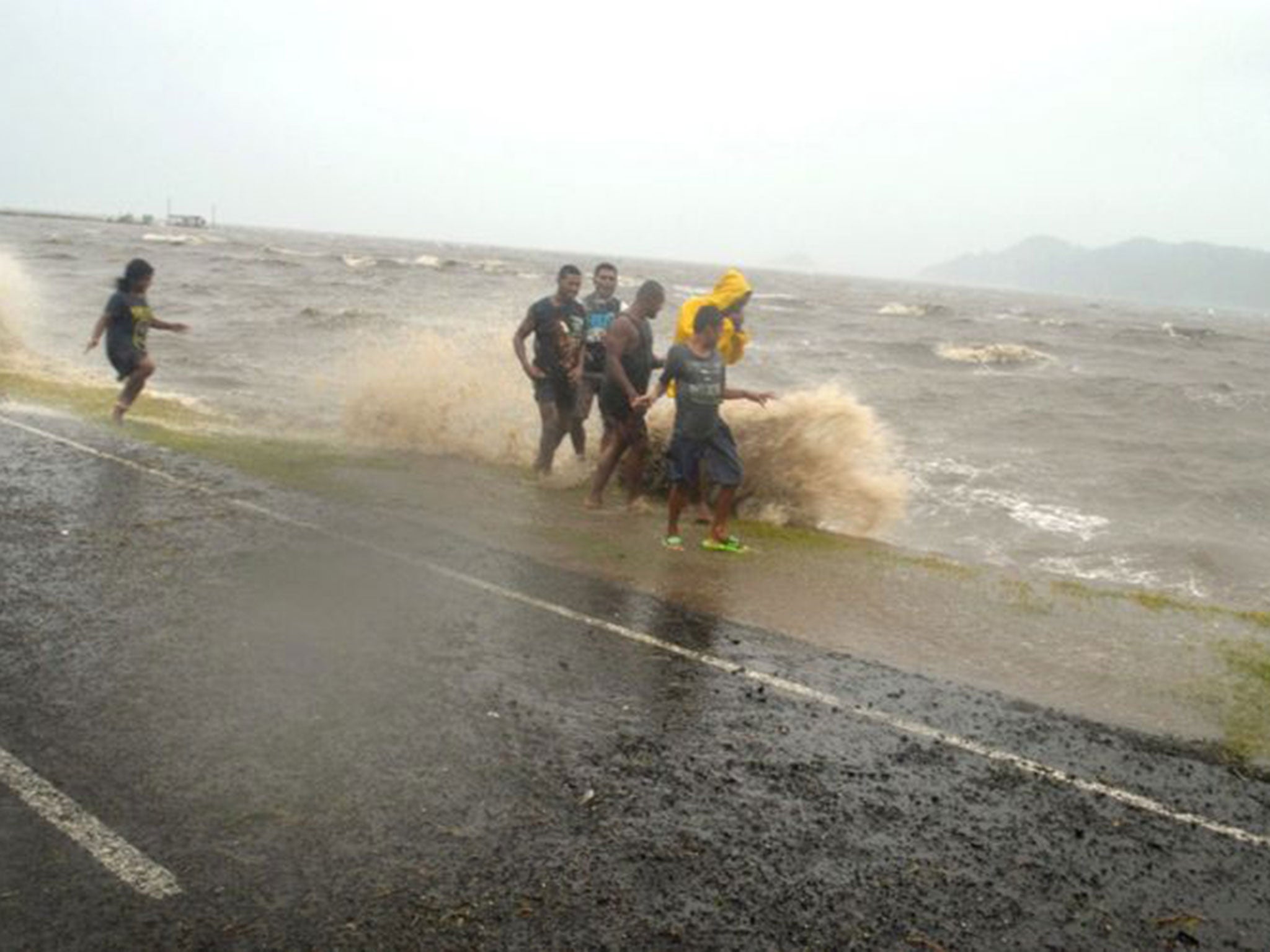 People are splashed by a wave whipped up by the encroaching cyclone Winston in Labasa, Fiji, Saturday, Feb. 20, 2016.