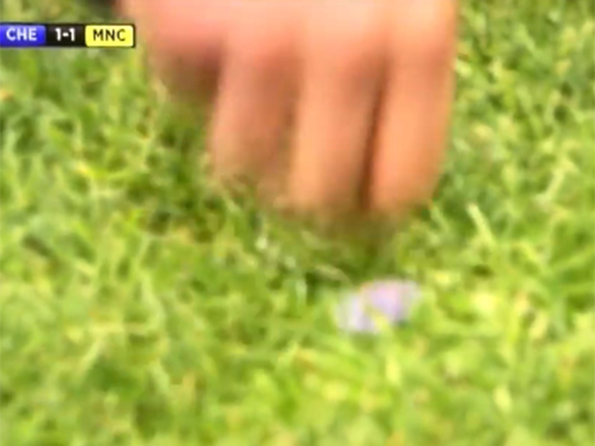 Referee Andre Marriner picks up a coin at Stamford Bridge