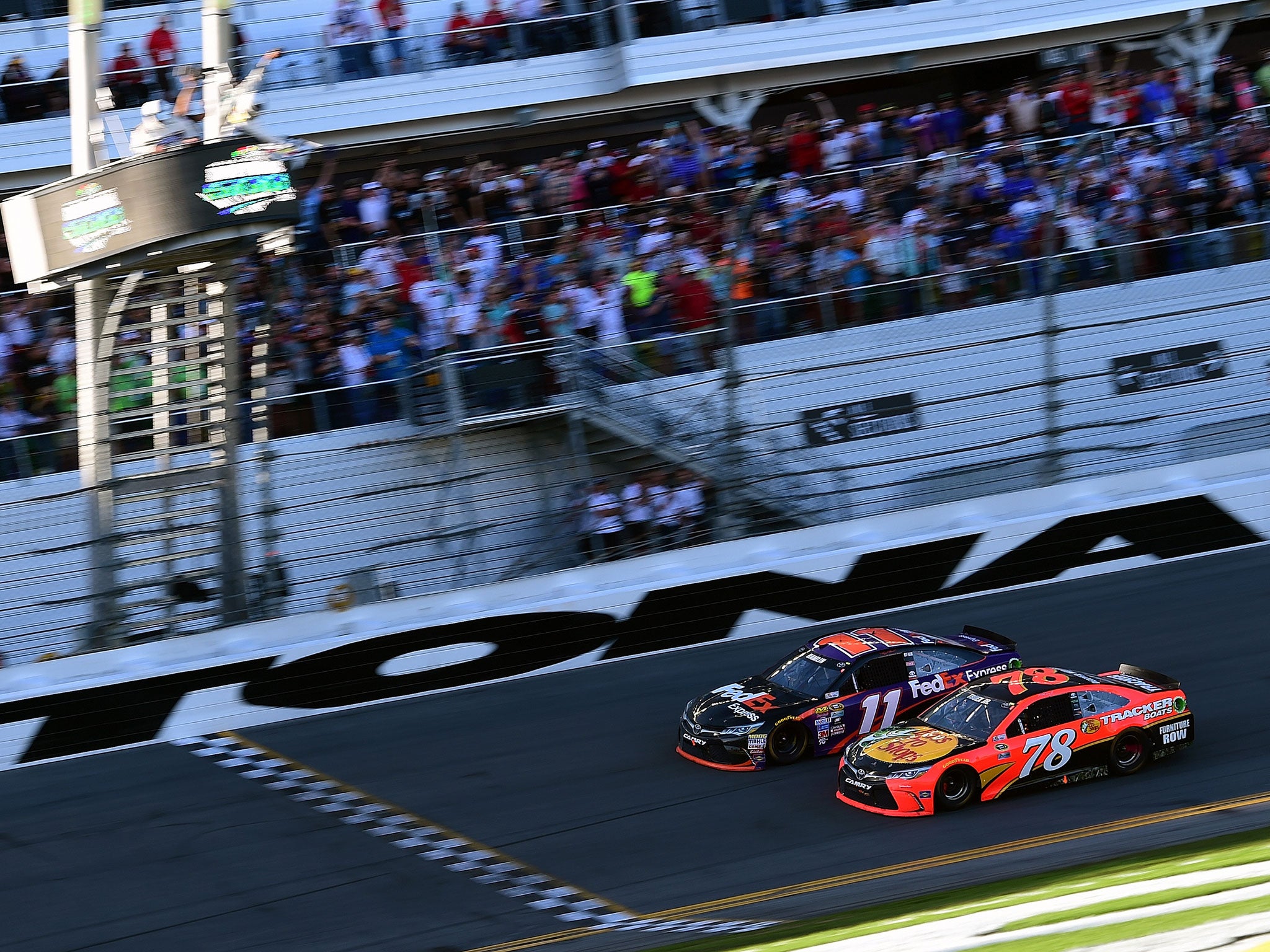 Dennny Hamlin, driver of the #11 FedEx Express Toyota, races to the finish line alongside Martin Truex Jr