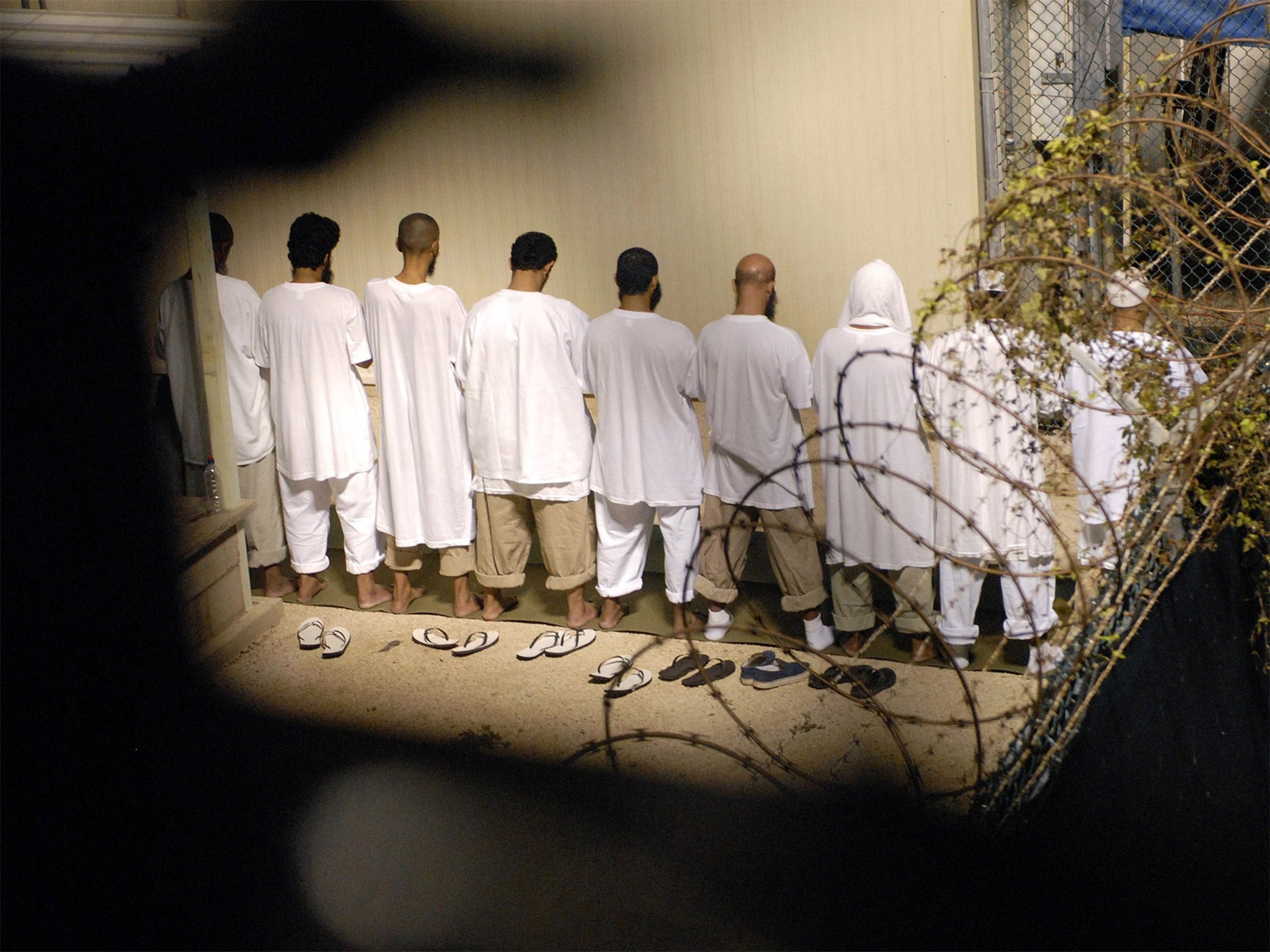 A group of detainees – pictured in 2009 – observing Muslim morning prayer before sunrise at Camp Delta at Guantanamo Bay