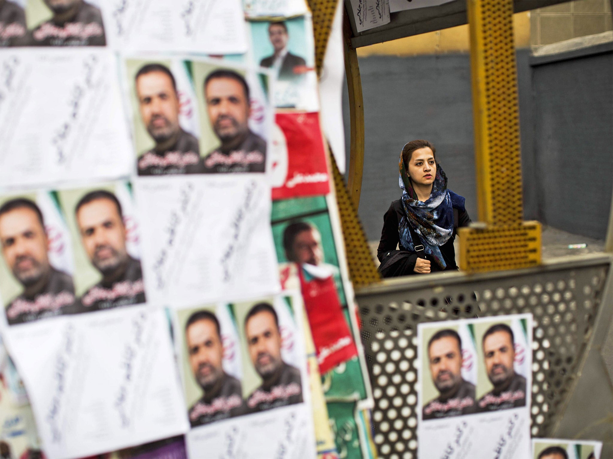 A woman walks past electoral posters for the upcoming elections in Tehran (Getty)