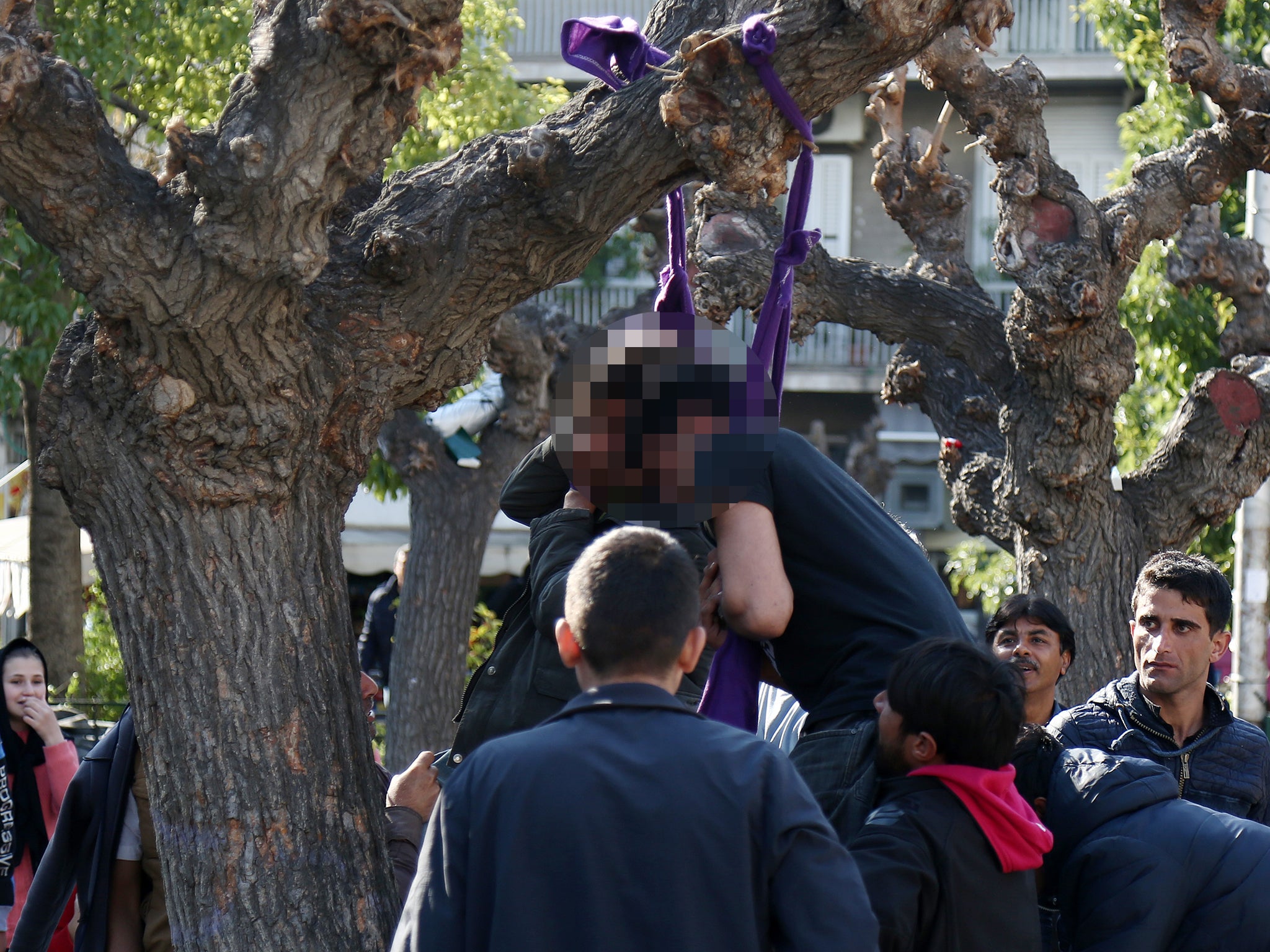 People rush to cut down two Pakistani refugees who tried to commit suicide by hanging themselves with twisted lengths of fabric from a tree in central Athens' Victoria Square. Bystanders said the men were upset because of delays in their planned travel to northern Greece, from which refugees start their long trek through the Balkans to wealthier European countries. The men, one of whom was unconscious, were rushed to hospital. Victoria Square is where most newly-landed migrants head after reaching Athens from the Aegean Sea islands